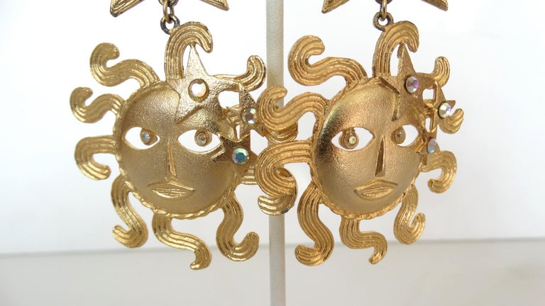 Embrace The Every Season With These Adorable Sun Goddess Earrings! Circa 1980s, these gold plated clip-on earrings features various stars and a beautifully detailed Baroque style sun. The sun includes small hanging rhinestones to mimic eyes.