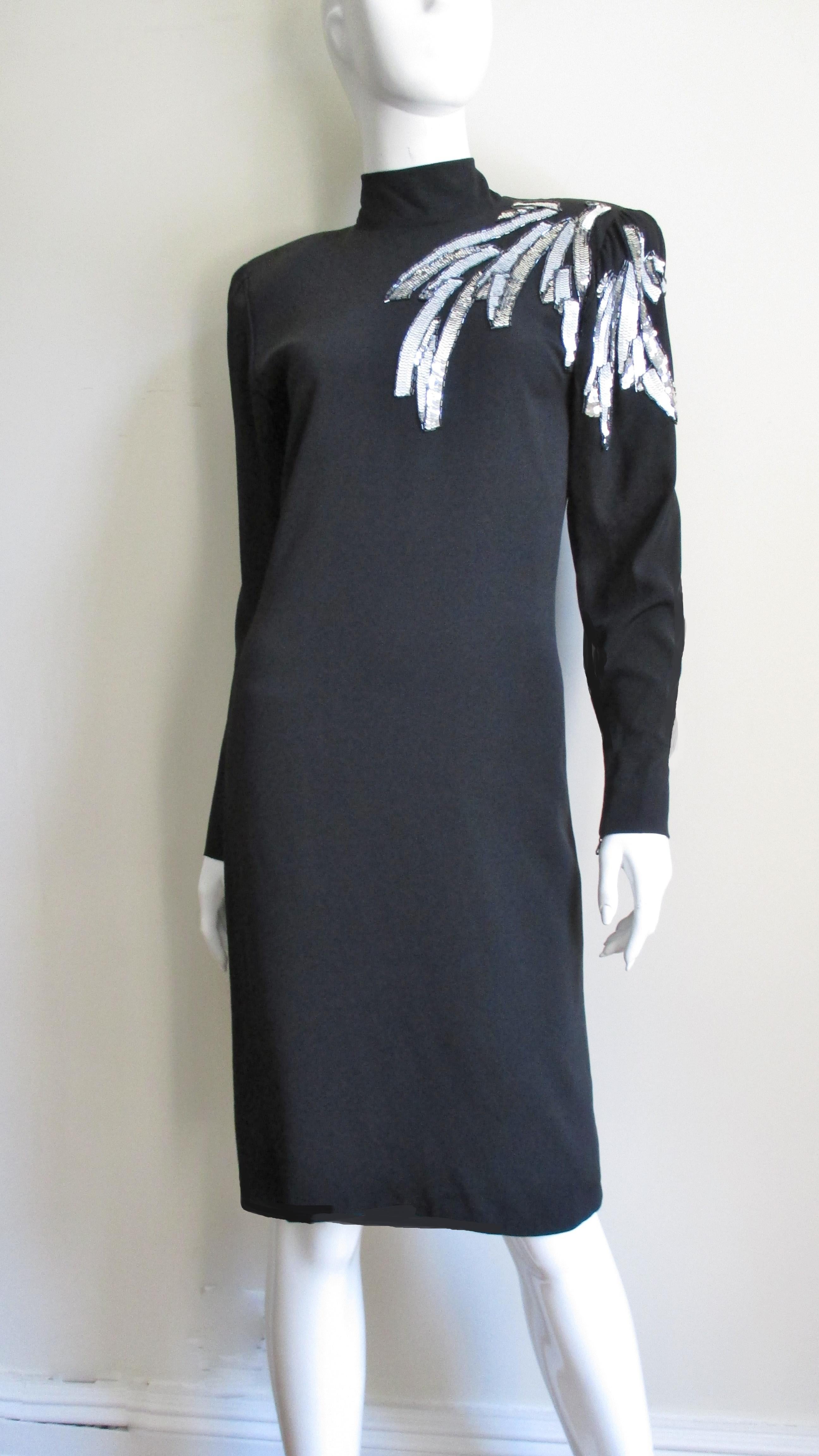 A fabulous black silk dress from Ted Lapidus.  It has long sleeves, a stand up collar and light shoulder padding.  There is a beautiful design in silver and white sequins outlined in dark silver glass tubular beads radiating from one shoulder-