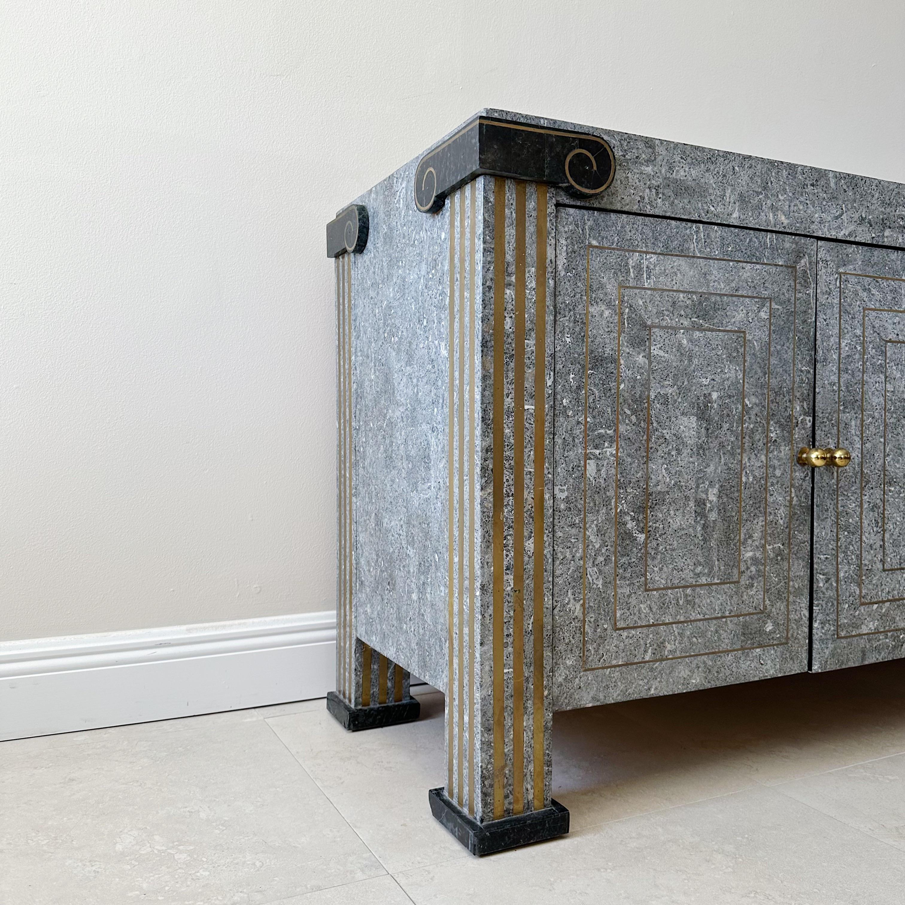 This exquisite sideboard credenza boasts a striking tessellated design in shades of gray, green, and black marble, accented with intricate brass inlay and door pulls. The cabinet's ends are elegantly crafted to resemble Greek columns, adding a touch