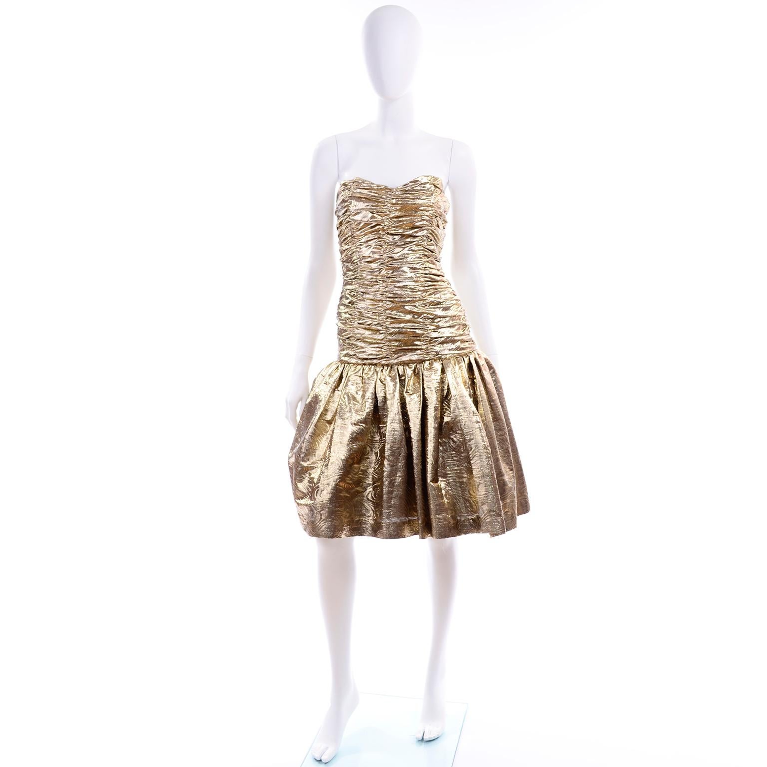 C'est une robe bustier en lurex doré texturé des années 80. Le corsage à taille basse est entièrement froncé et la jupe est doublée d'un jupon de tulle pour plus d'ampleur.  La robe est entièrement doublée en satin et se ferme avec une fermeture