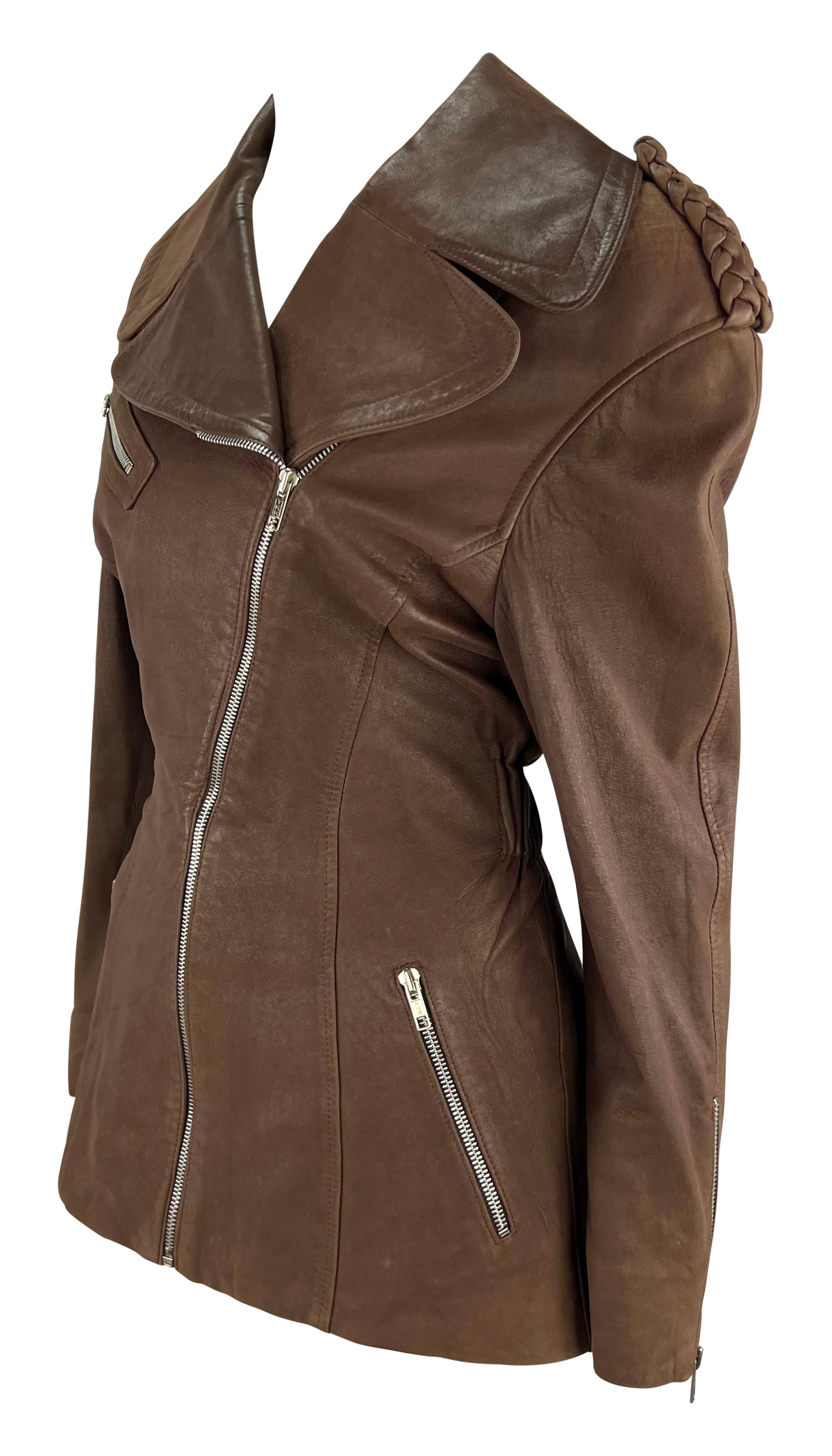 This striking brown leather moto jacket by Thierry Mugler was designed by Manfred Mugler in the late 1980s. Crafted from soft leather, this chic coat features a fold-over collar, braided epaulettes, and an asymmetric zipper for added style. The