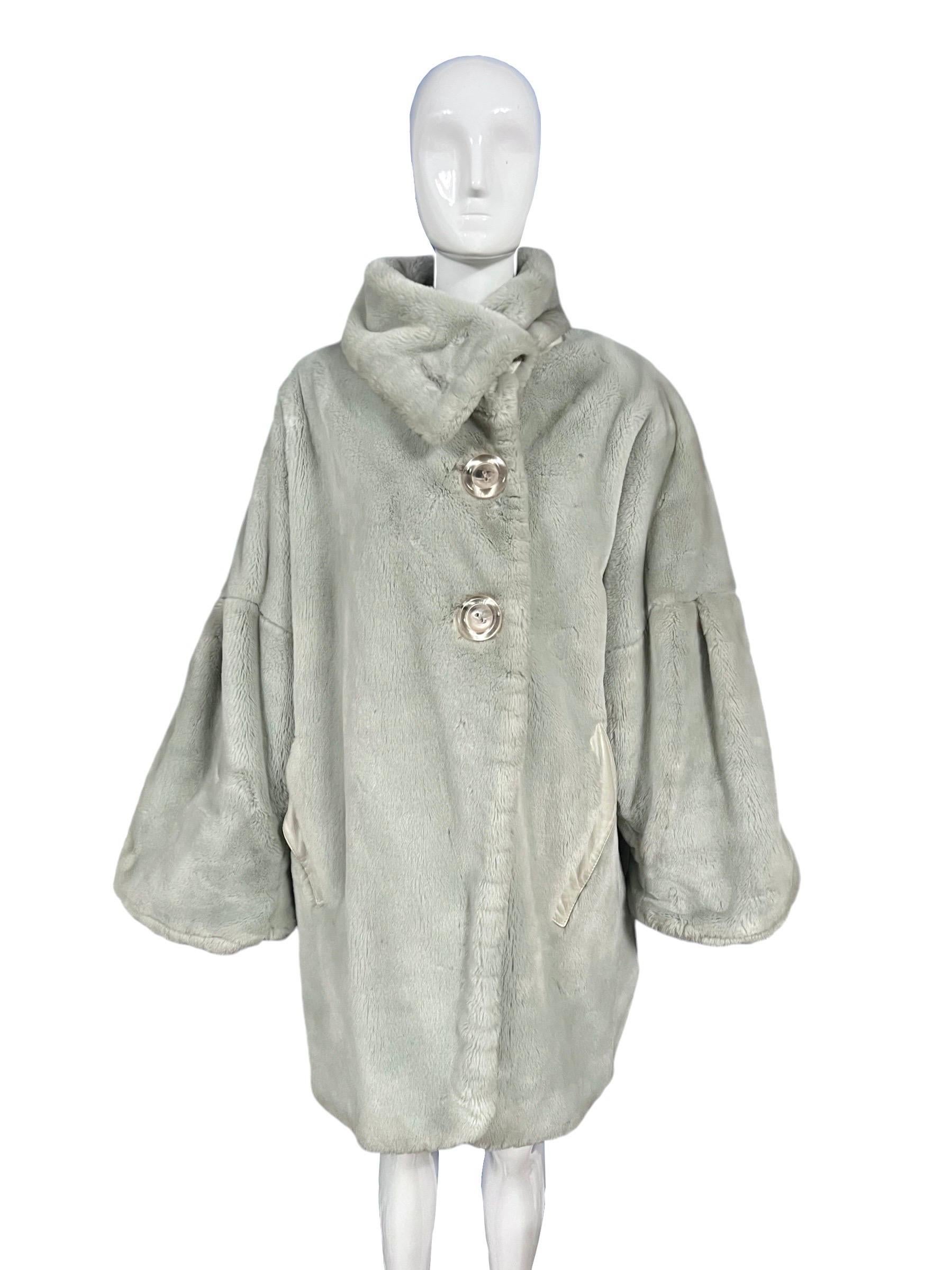 Create a statement in this Thierry Mugler gray faux fur coat from the 1980’s. This coat features an oversized design with wide sleeves, exaggerated shoulders, and a large fold down collar. Large clear buttons. Ivory leather trim. 

Size: FR