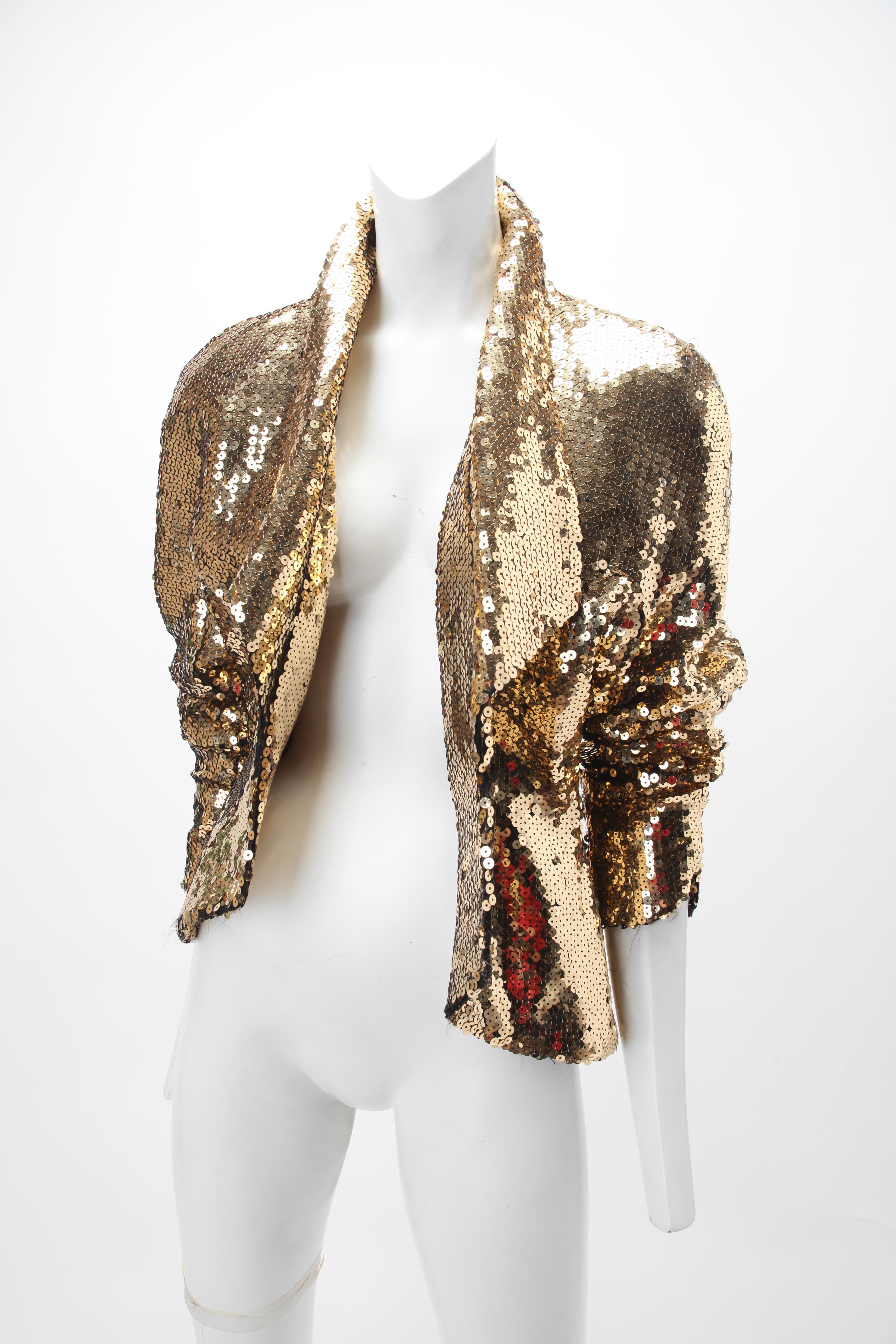 1980s Thierry Mugler Gold Sequin Jacket; Fitted jacket with lapels, gathered at waist with three gold metal snap closures; Dolman sleeves with notch at cuffs; Fully lined. Labeled Thierry Mugler Paris. Size 40. Fits US size 4. Some sequin loss which