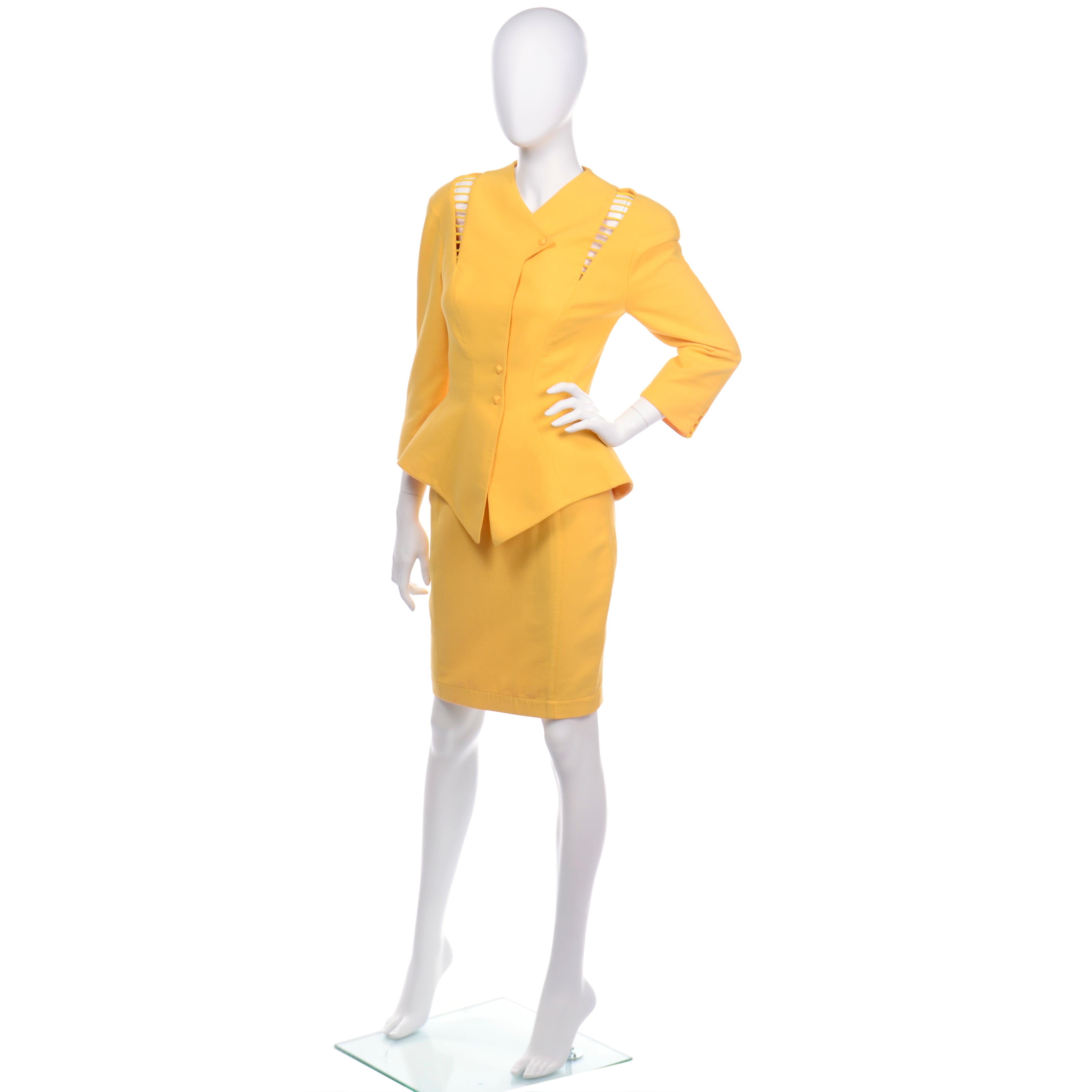 This is an iconic Thierry Mugler skirt suit in a marigold or yellow marigold pique . The jacket is fitted in the dramatic Mugler peplum style and it has incredible cutwork near the shoulders on both sides and on the cuffs. The jacket is fully lined