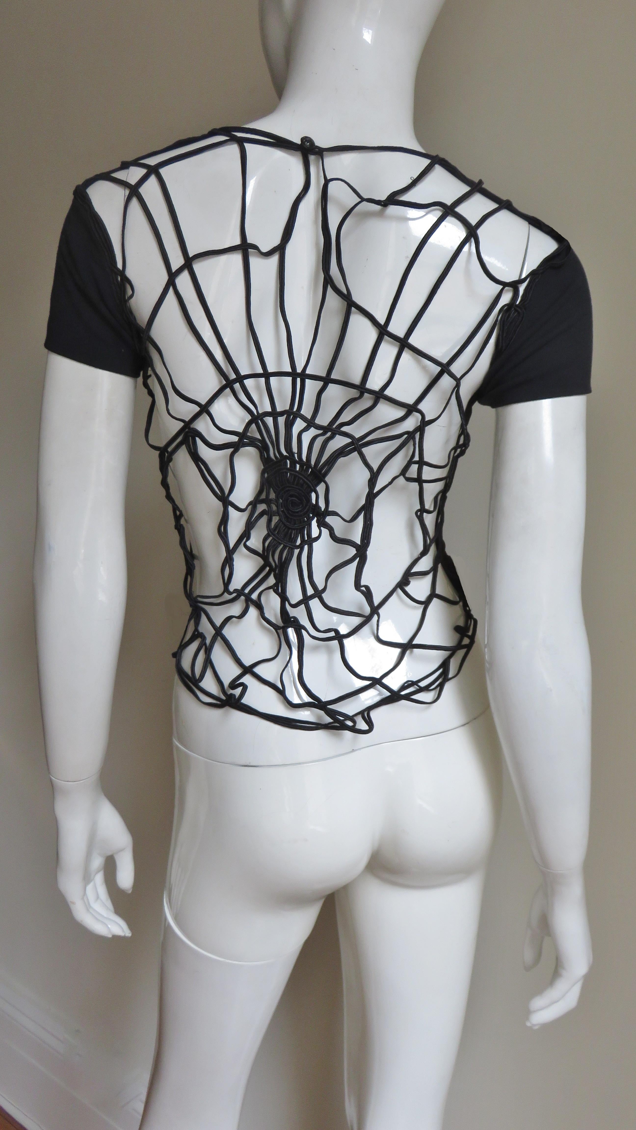 Ein fabelhaftes schwarzes Baumwoll-T-Shirt von Todd Oldham.  Ein einfaches kurzärmeliges T-Shirt von vorne, aber die Rückseite ist ein kompliziertes Seidenschnur-Spinnennetzmuster.  Sie wird über den Kopf gezogen und hat einen Knopf und eine