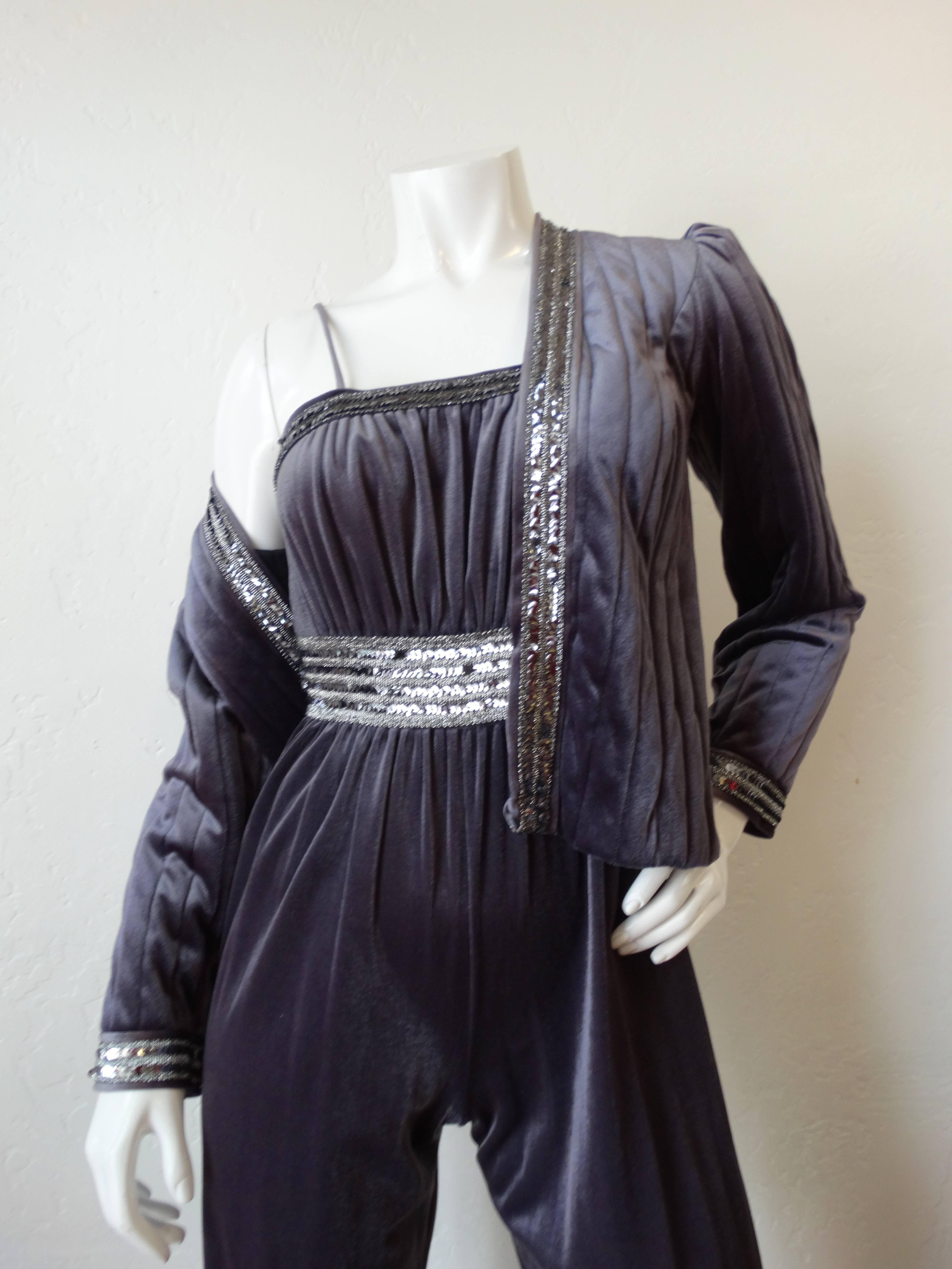 Channel your inner disco queen with our amazing 1980s velvet jumpsuit! Made of a soft, shiny grey velvet accented with silver sequin band around the waist and trim of the jacket. Jumpsuit has a flattering gathered bust with sexy spaghetti straps.