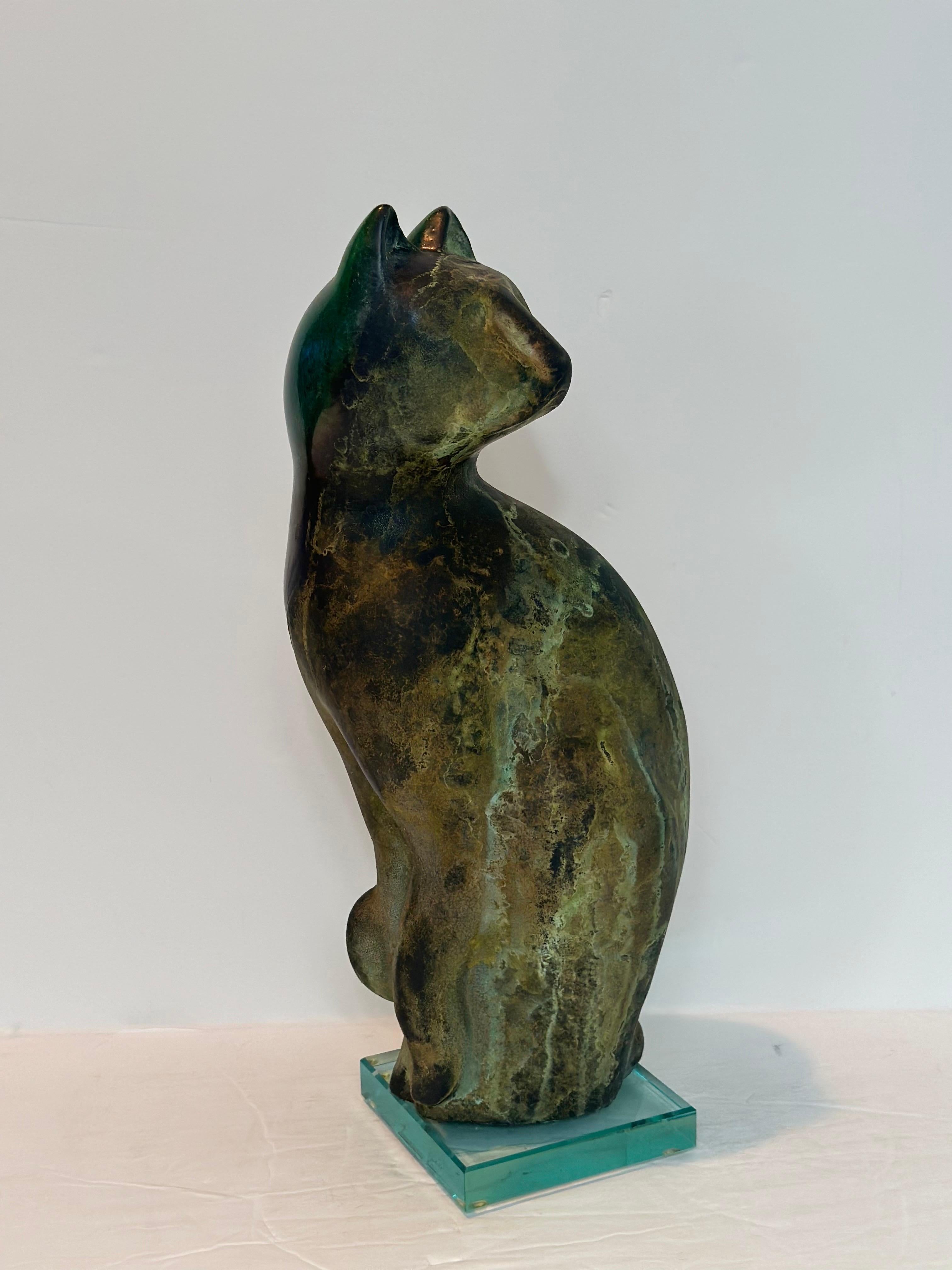 Nos complace ofrecer una cautivadora escultura de gato de cerámica raku del ceramista estadounidense Tony Evans, firmada por el artista, de hacia la década de 1980.  Esta exquisita pieza presenta distintos tonos verdes y vetas verdes naturales,