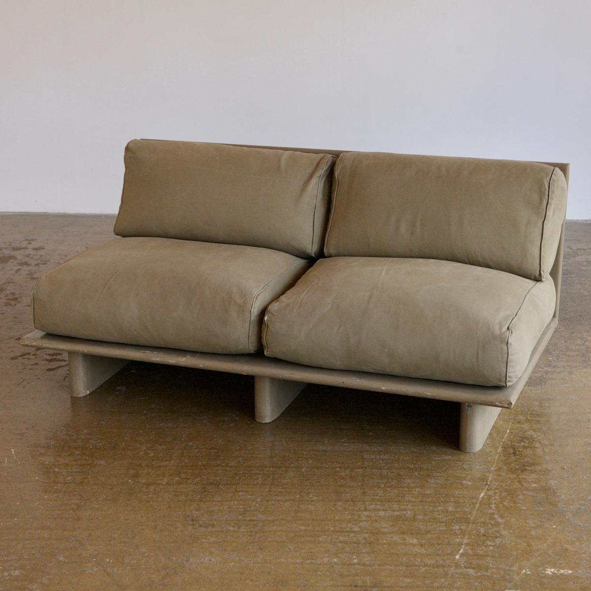 Giant feather stuffed cushions make up the seats for this excellent minimalist sofa from 1980's France. It's has a futon style construction but isn't too low and is incredibly comfortable. The frame matches the cotton twill fabric in a muted khaki