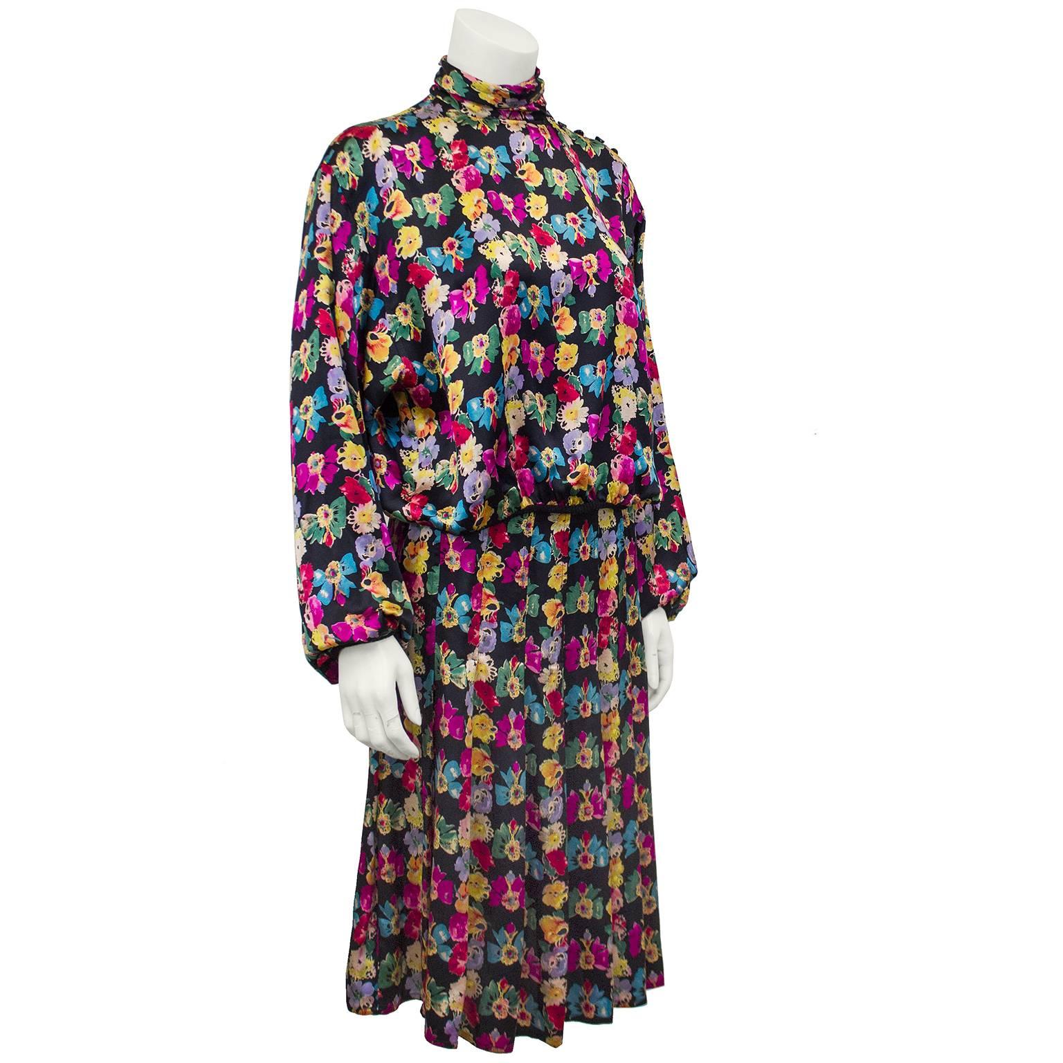 1980s Ungaro silk floral top and skirt ensemble. Black with multi color all over floral print. Turtleneck with buttons across the shoulder and up neck. Top is cropped with dolman sleeves. Black knit ribbed trim at hem at cuffs. Skirt is high waisted