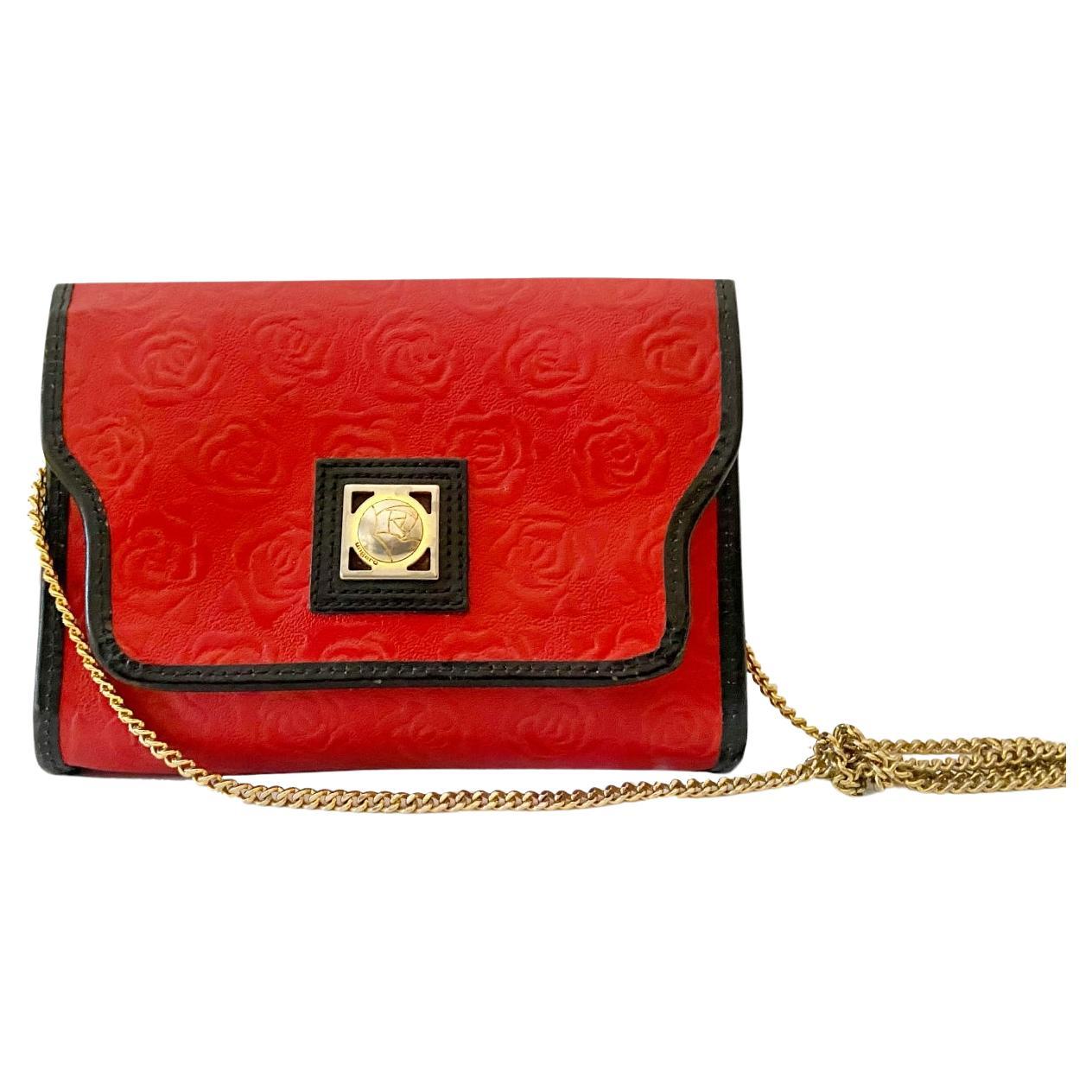 Parisian opulence in this 1980s Ungaro Paris Red Embossed Shoulder bag with gold chain, the sumptuous red embossed leather, accented with sleek black details, radiates sophistication and refinement. Adorned with shimmering gold-tone hardware, the