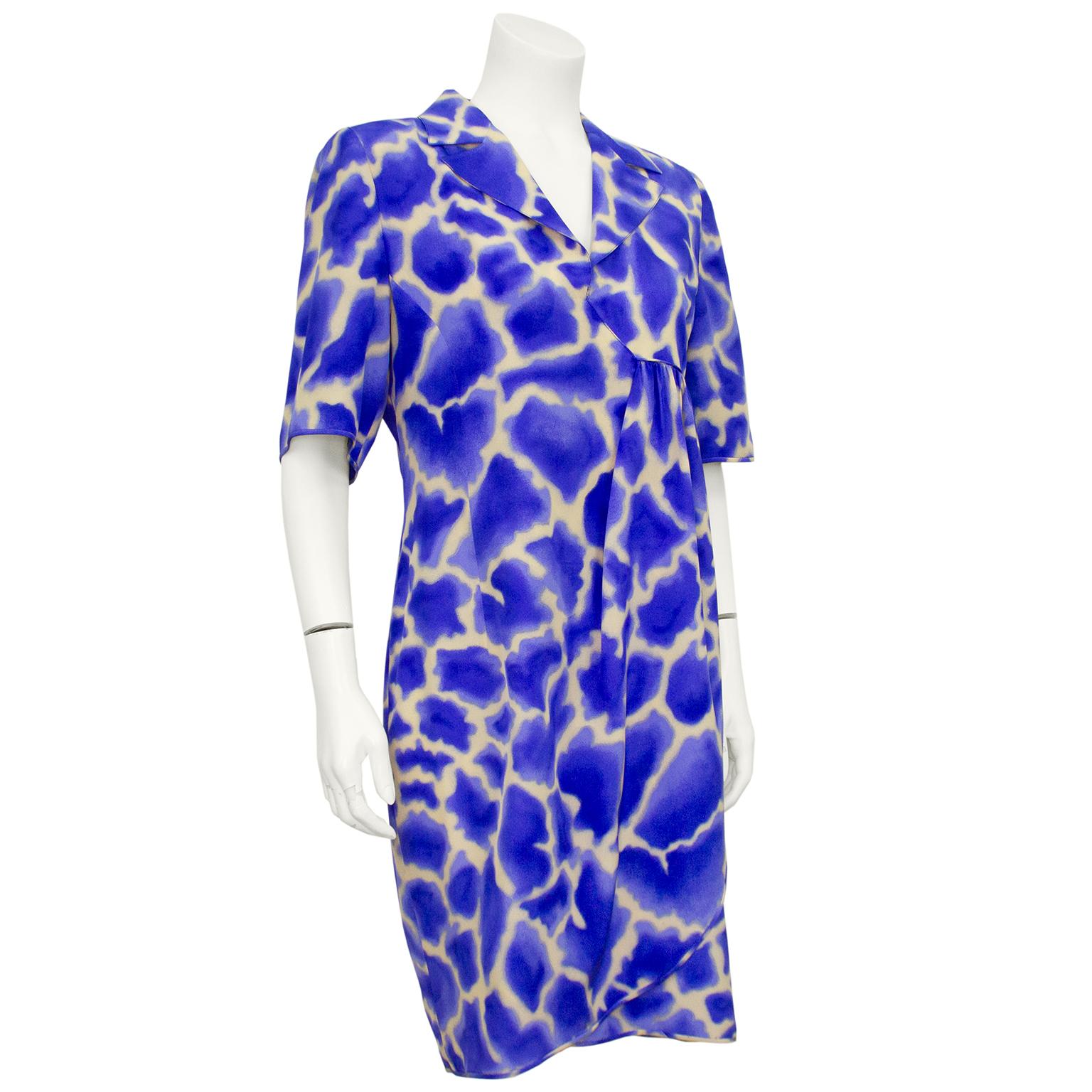 Vibrant and unique Valentino dress from the 1980s. All over blue and beige abstract giraffe print. Short sleeve with notched collar and v neckline. Asymmetrical waist with ruching on left side of the body that creates a faux wrap dress shape. Tulip
