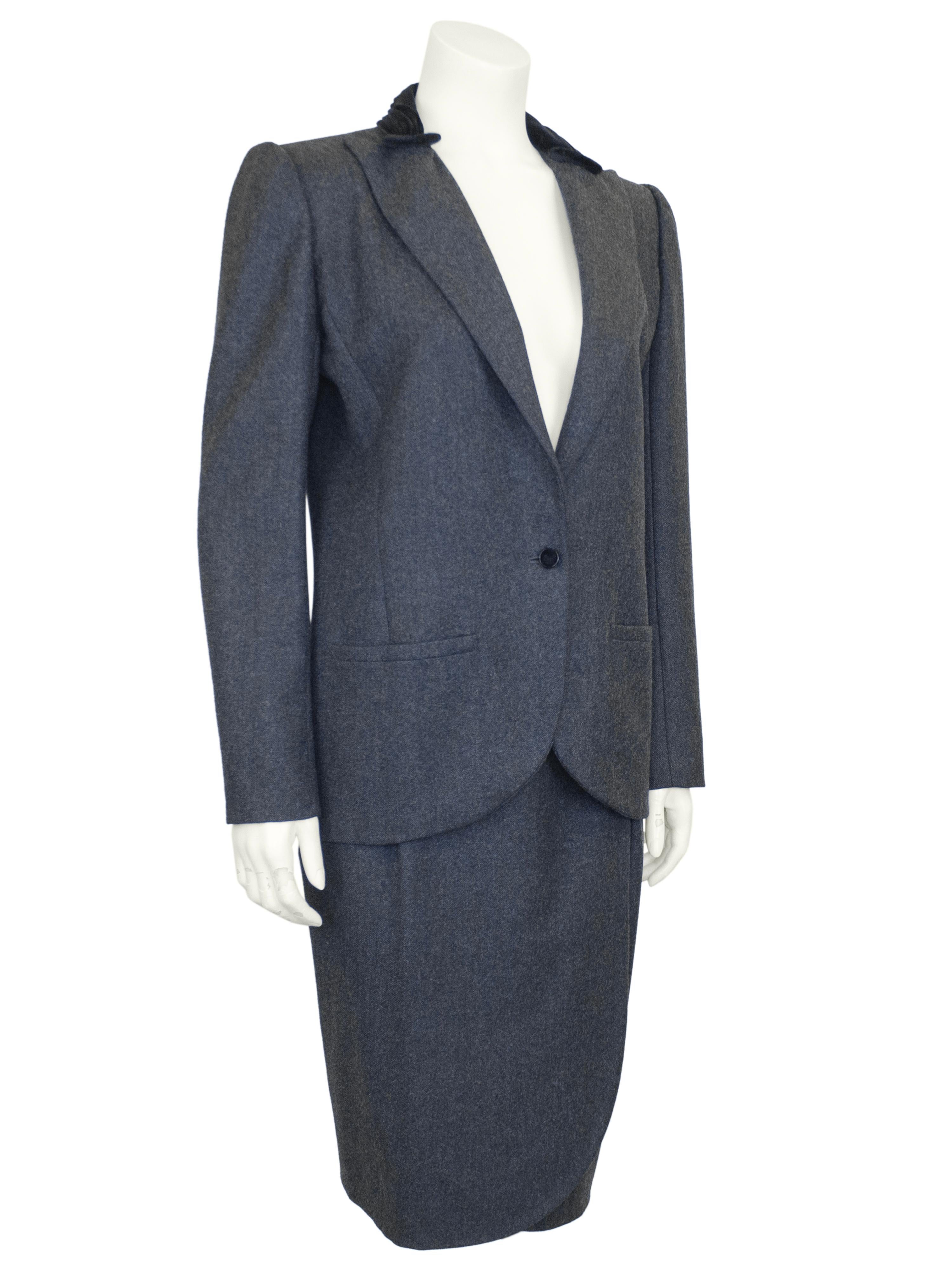 Lovely Valentino dark grey wool skirt suit from the 1980s. The suit features a minimal, classic single button blazer with an interesting black velvet collar detail. The rounded hem of the blazer mimics the tulip hem of the skirt beautifully. The
