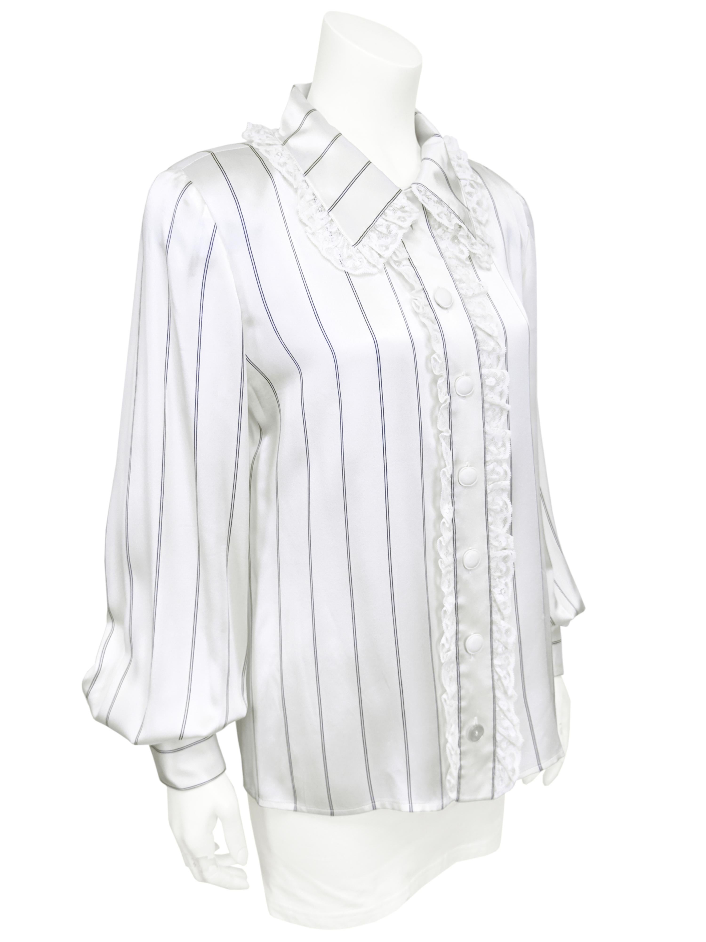 1980's Valentino blouse crafted from a luxurious off white silk with a navy blue vertical pin stripe. Off white lace trim at the collar, down the centre front and at the french cuffs. Cream rounded square buttons - bottom button is mother of pearl.