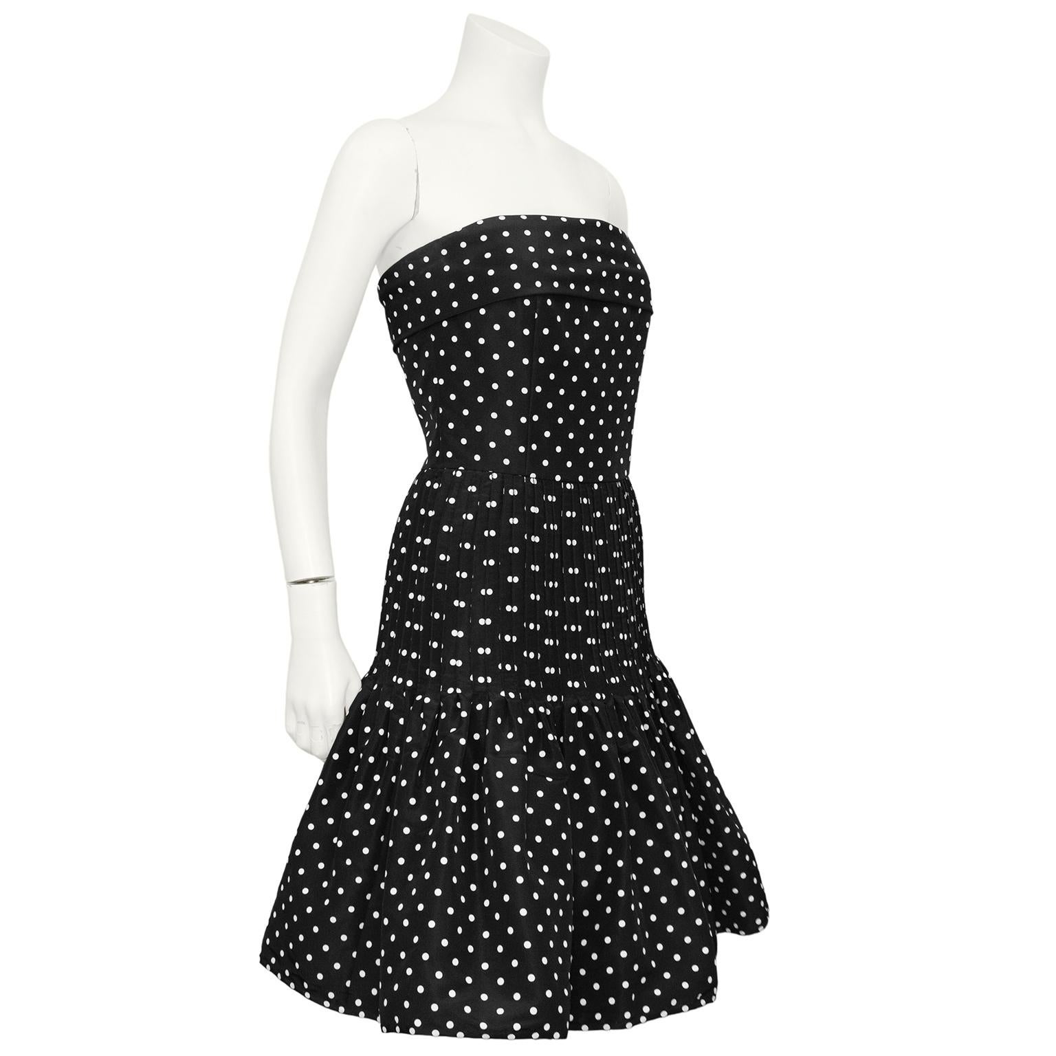 Fun and flirty 1980s Valentino black and white polka dotted strapless cocktail dress. the Top of the dress has a wide folded panel, is nipped in at the waist and the skirt is fitted through the hips with a pintuck detail. The interior is constructed