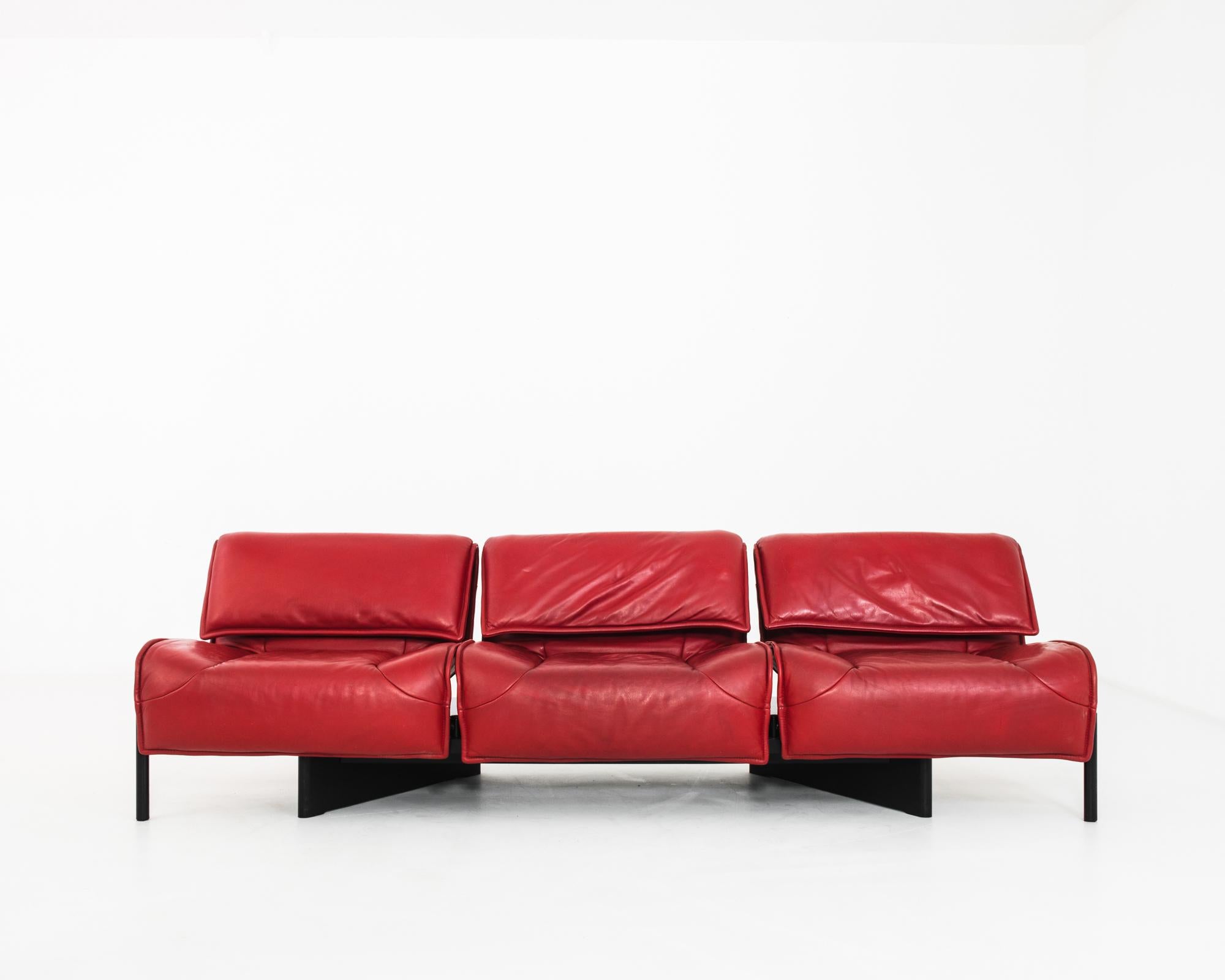 A Veranda model 3-seater sofa, designed by renowned Italian Industrial designer Vivo Magistretti for Cassina in the 1980s. Three seats, upholstered in bright burgundy leather, swivel on their axes to allow a range of seating configurations — from