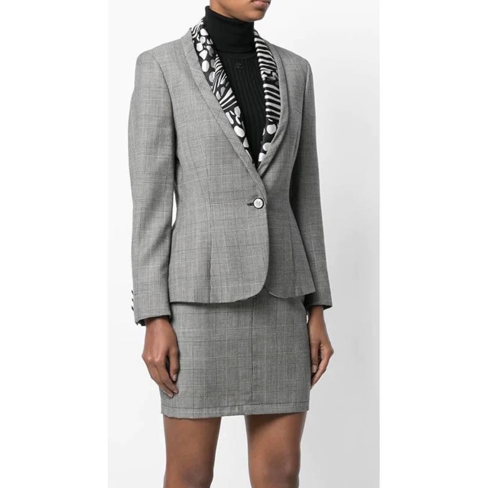 Versace grey silk and wool blend Prince of Wales suit. Shawl collar jacket with contrasting black and white pattern, front button closure, long sleeves; straight cut high-waist mini skirt.

Size: 44 IT

Flat measurements
Jacket
Bust: 46