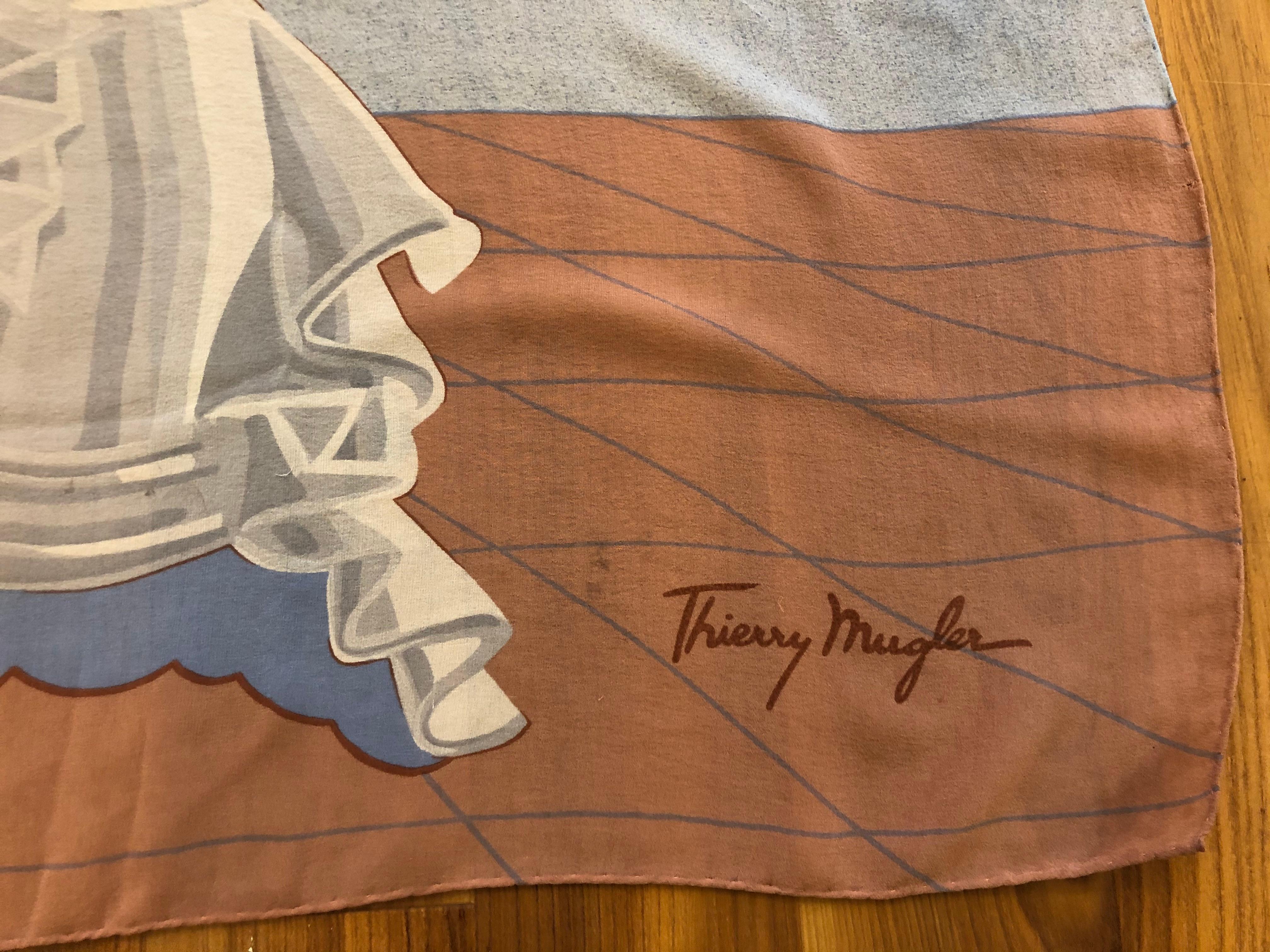 This is a superb Thierry Mugler silk chiffon scarf with Dali inspired graphics from the surrealist movement. In fact, Dali designed perfume bottles for Thierry Mugler.

The background of this scarf is grey/blue, with blue, grey and orange tones.