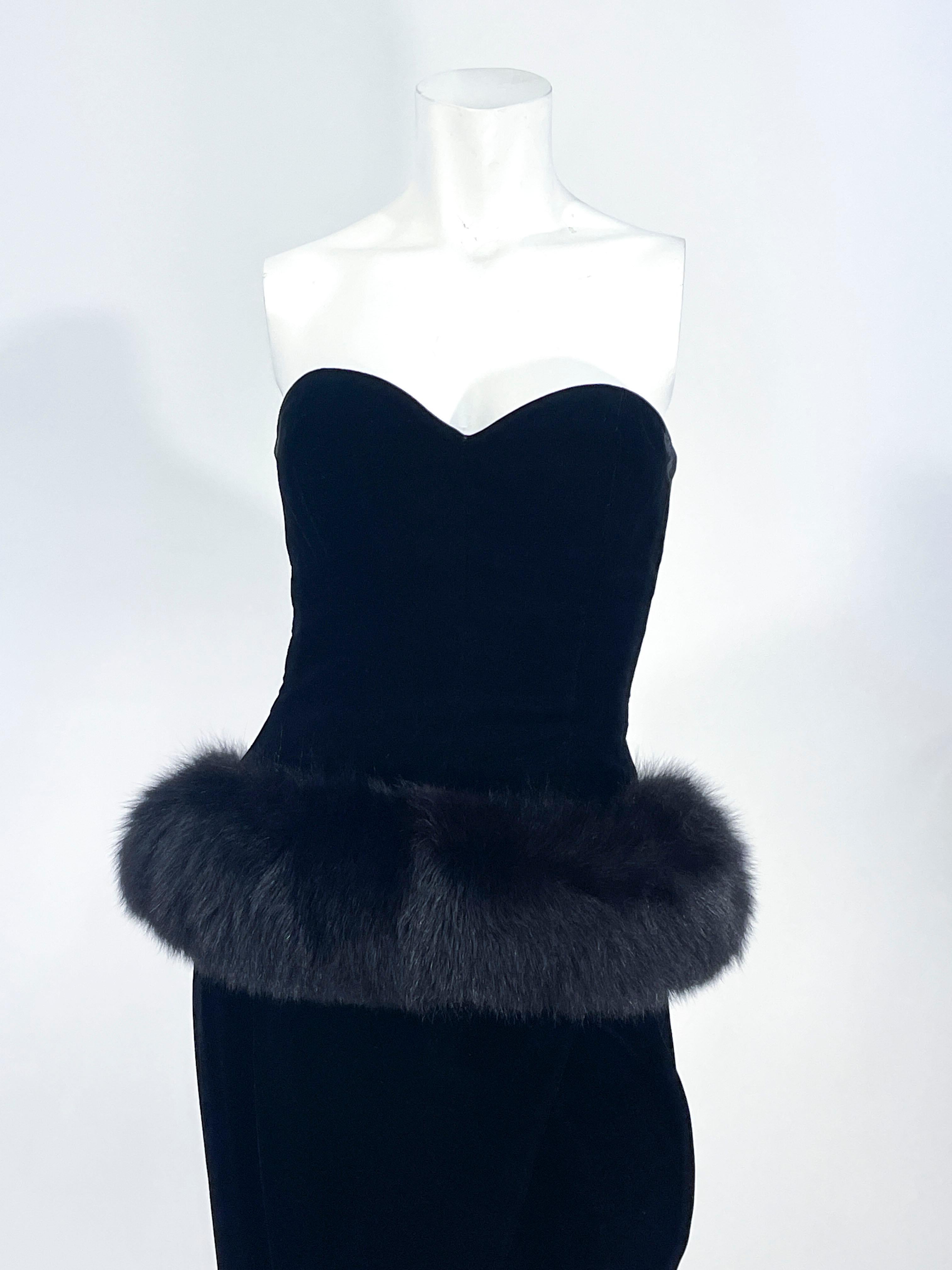 1980s Victor Costa black velvet strapless column dress. The fitted bodice has a sweetheart neckline and interior boning for structure down to the waist. The waist features an enlarged black fox fur peplum that hugs to the back of the waist. The wrap