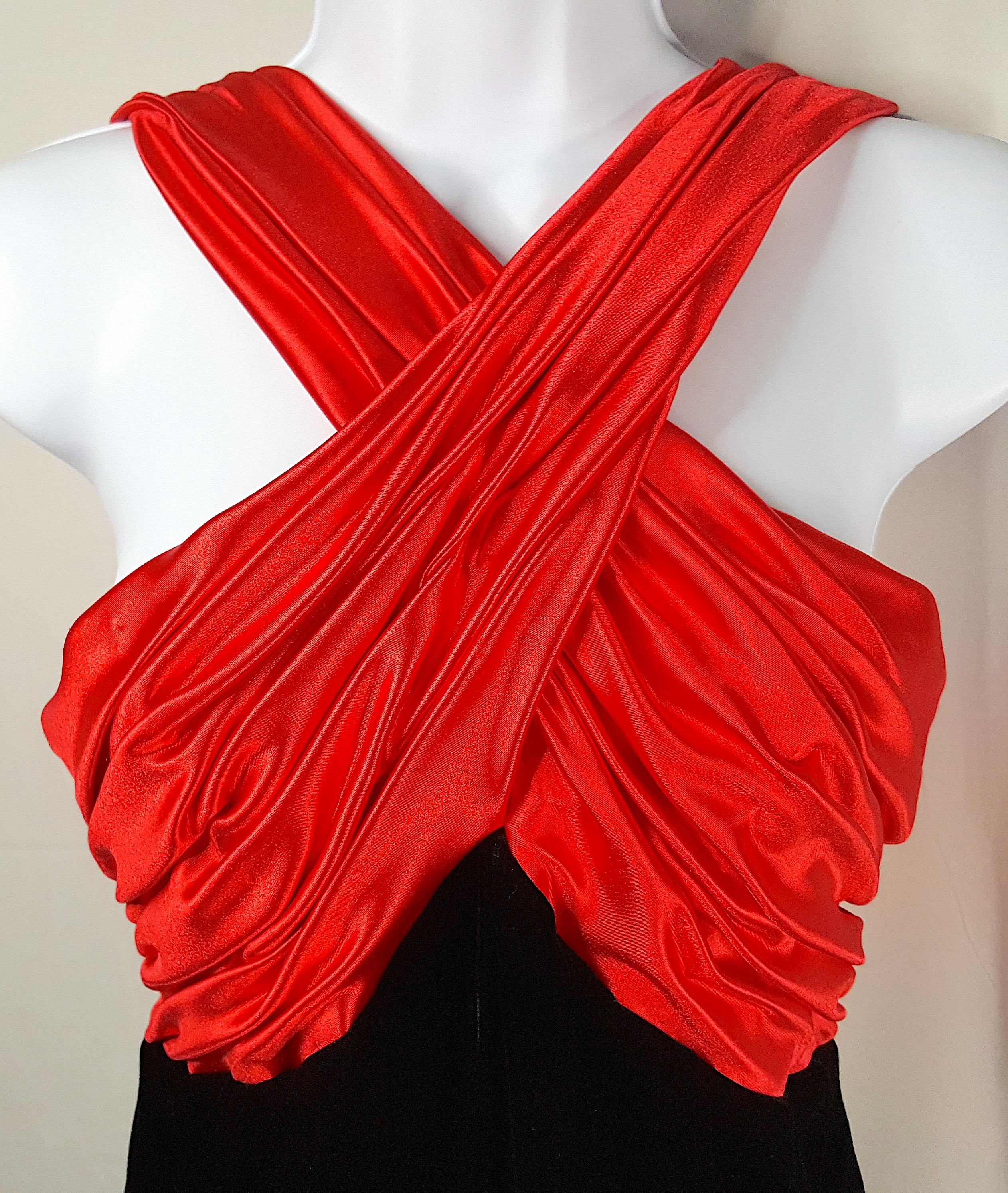 For a formal special event, this 1980s maxi dress sleeveless gown by American designer Victor Costa features glamorous glossy red satin that is gathered, ruched and topstitched in both front and back to create the crossing bands above the peaked and