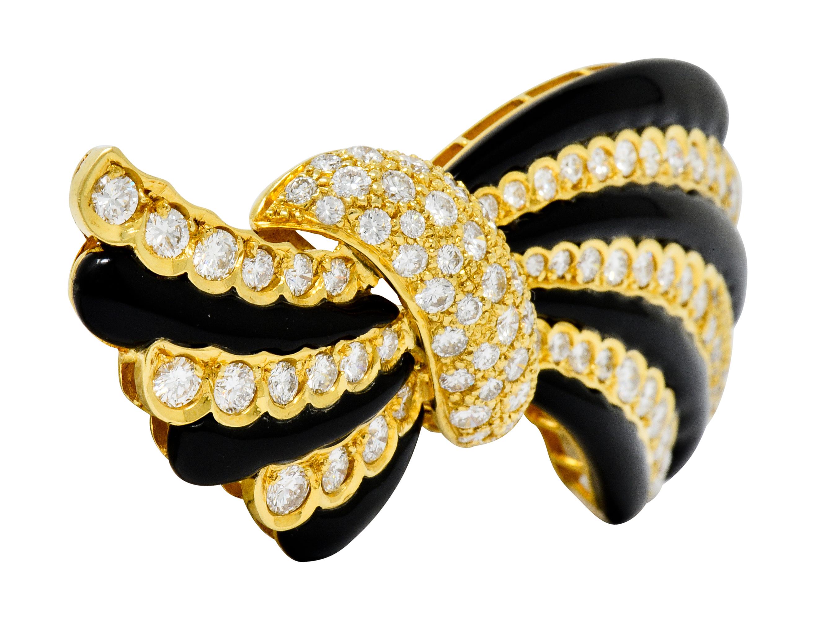 Brooch is designed as a stylized bow motif, contraposto, with black onyx stripes alternating with rows of diamonds and a pavè diamond center

Rows of diamonds feature an elegantly scalloped gold edge flush set against the calibrè cut onyx, excellent