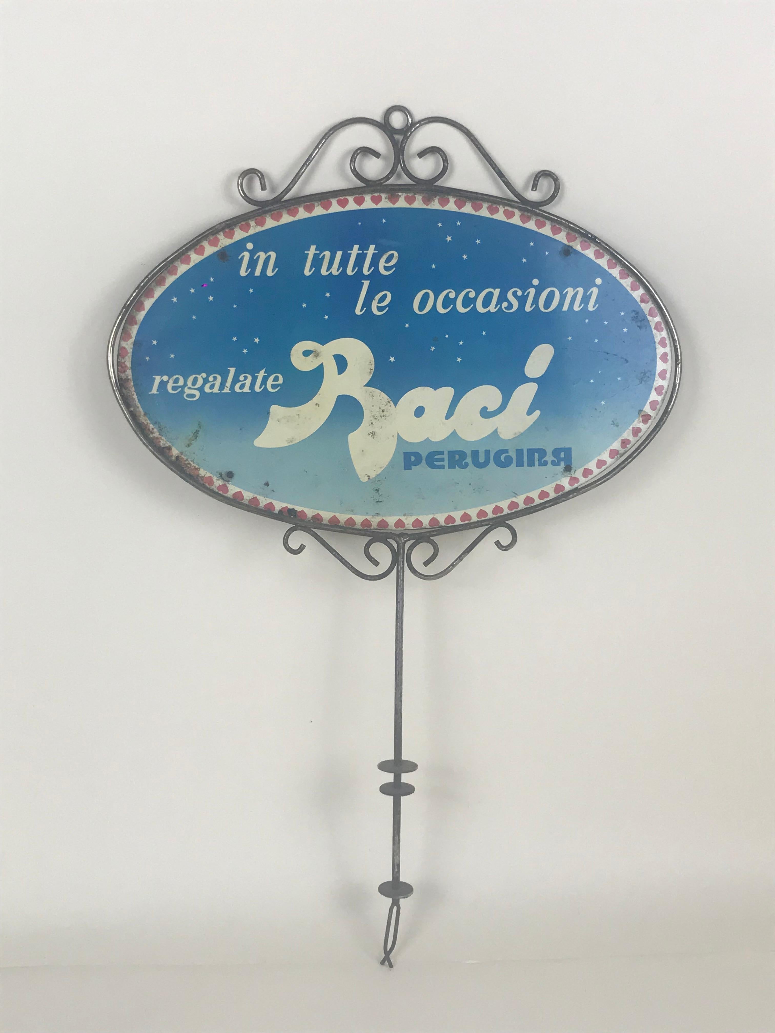 1980s vintage Baci Perugina short advertising pole with two screen printed oval signs (front and back). 

This object was displayed on top of product dispenser in various commercial venues.

Each sign runs the slogan: 