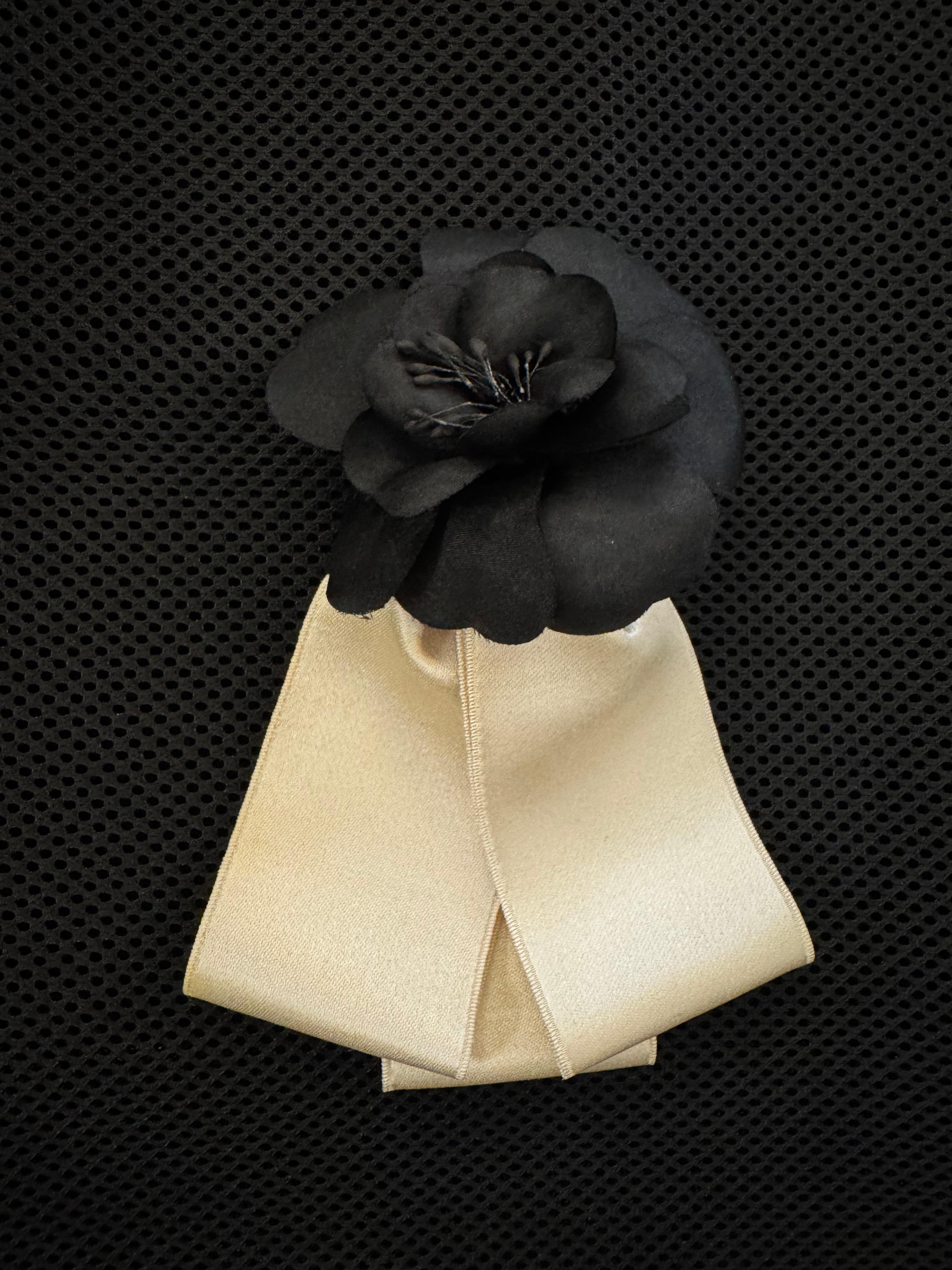 This vintage CHANEL camellia brooch is crafted of off-white ribbons adorned with a black polyester camellia. Stamped CHANEL made in France. Measures approximately 14 x 7 cm. Comes with box and tag.

Condition: Very good vintage condition with