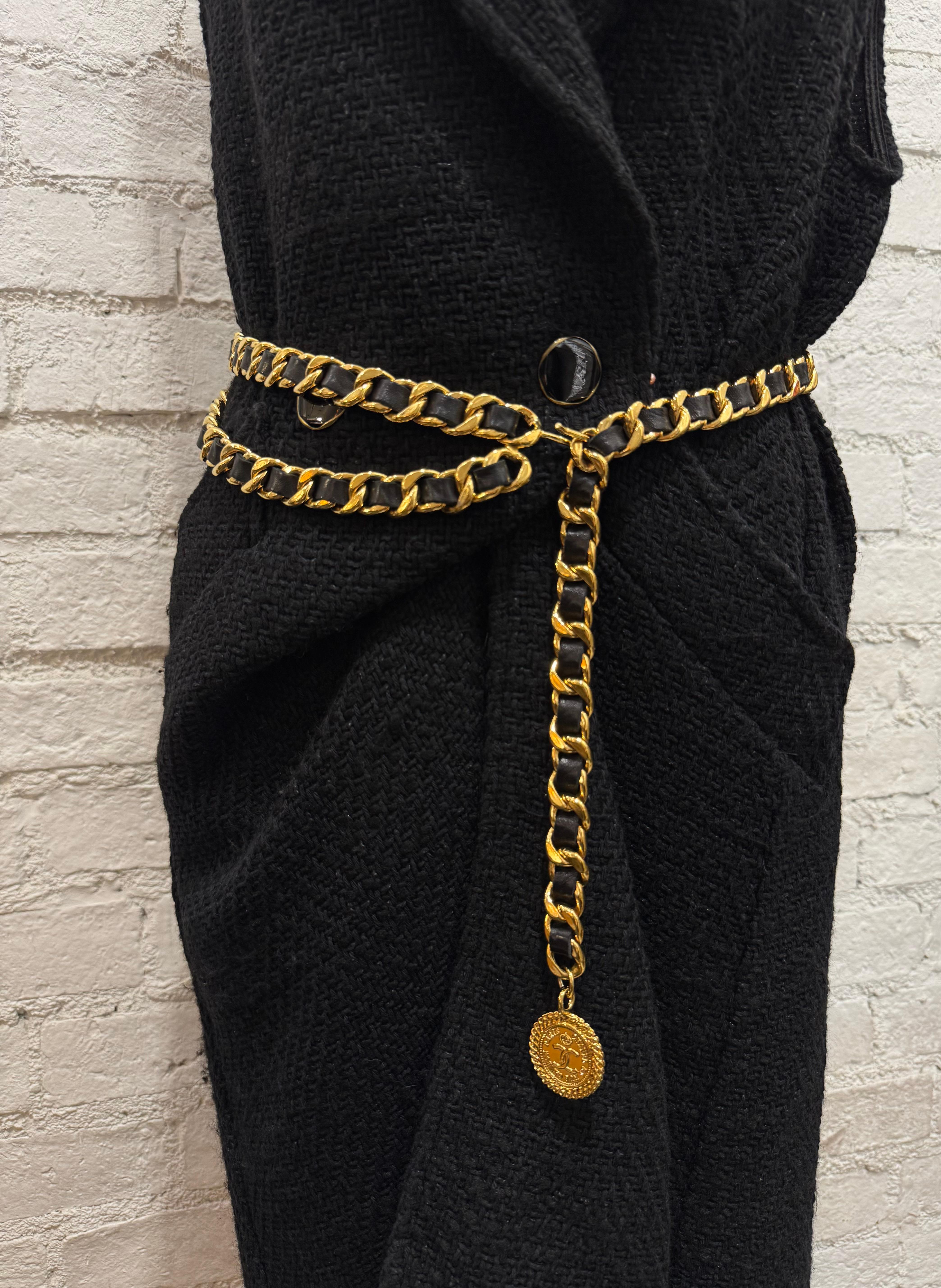 Cette ceinture en cuir CHANEL vintage des années 1980 est composée de solides chaînes dorées entrelacées de cuir d'agneau noir, d'une double chaîne drapée sur le devant et d'une breloque en forme de pièce de monnaie COCO CHANEL. Estampillé CHANEL.
