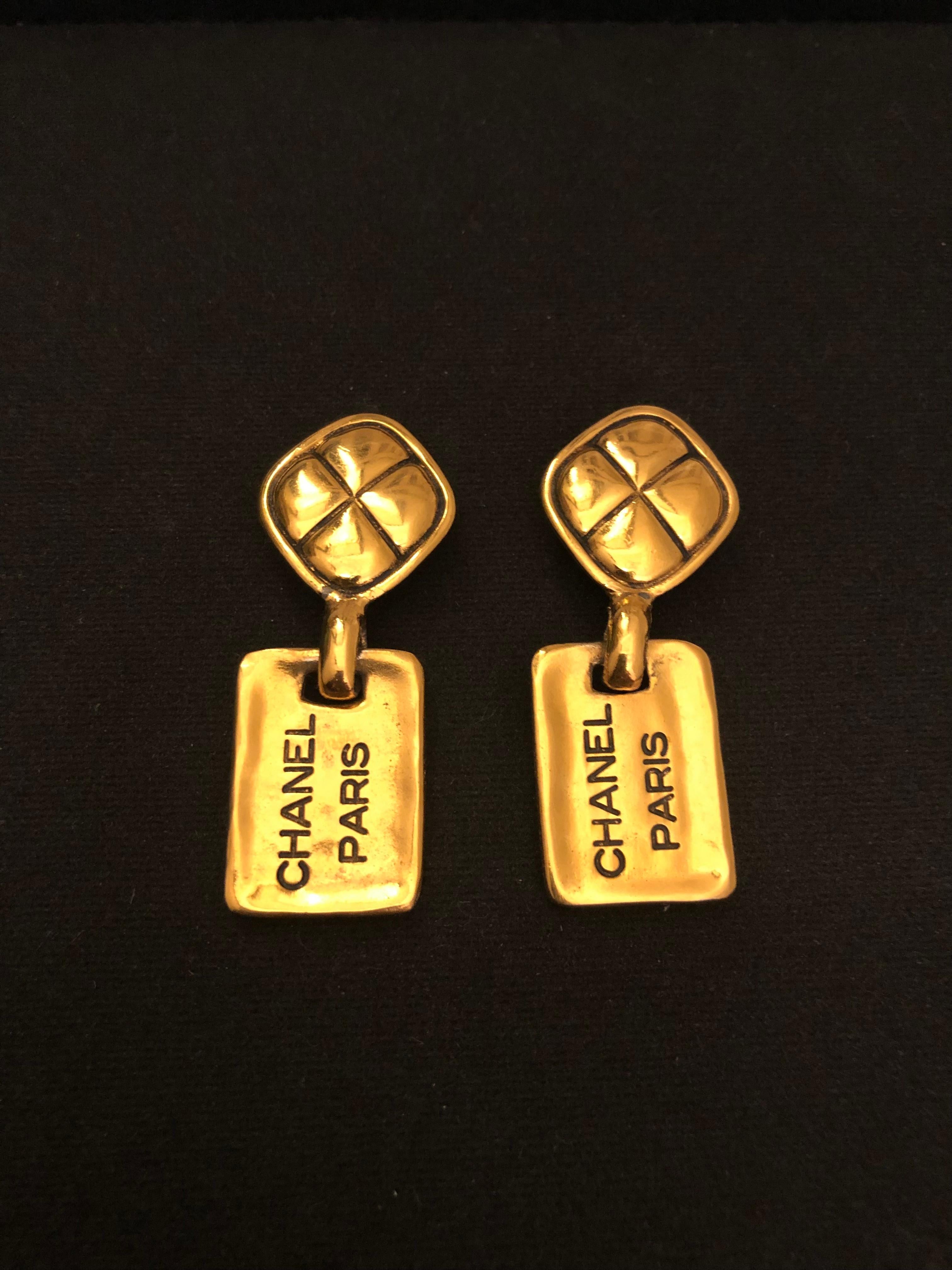 Clips d'oreilles pendants Vintage CHANEL en or, avec un clip en forme de diamant matelassé et une plaque pendante portant la mention 