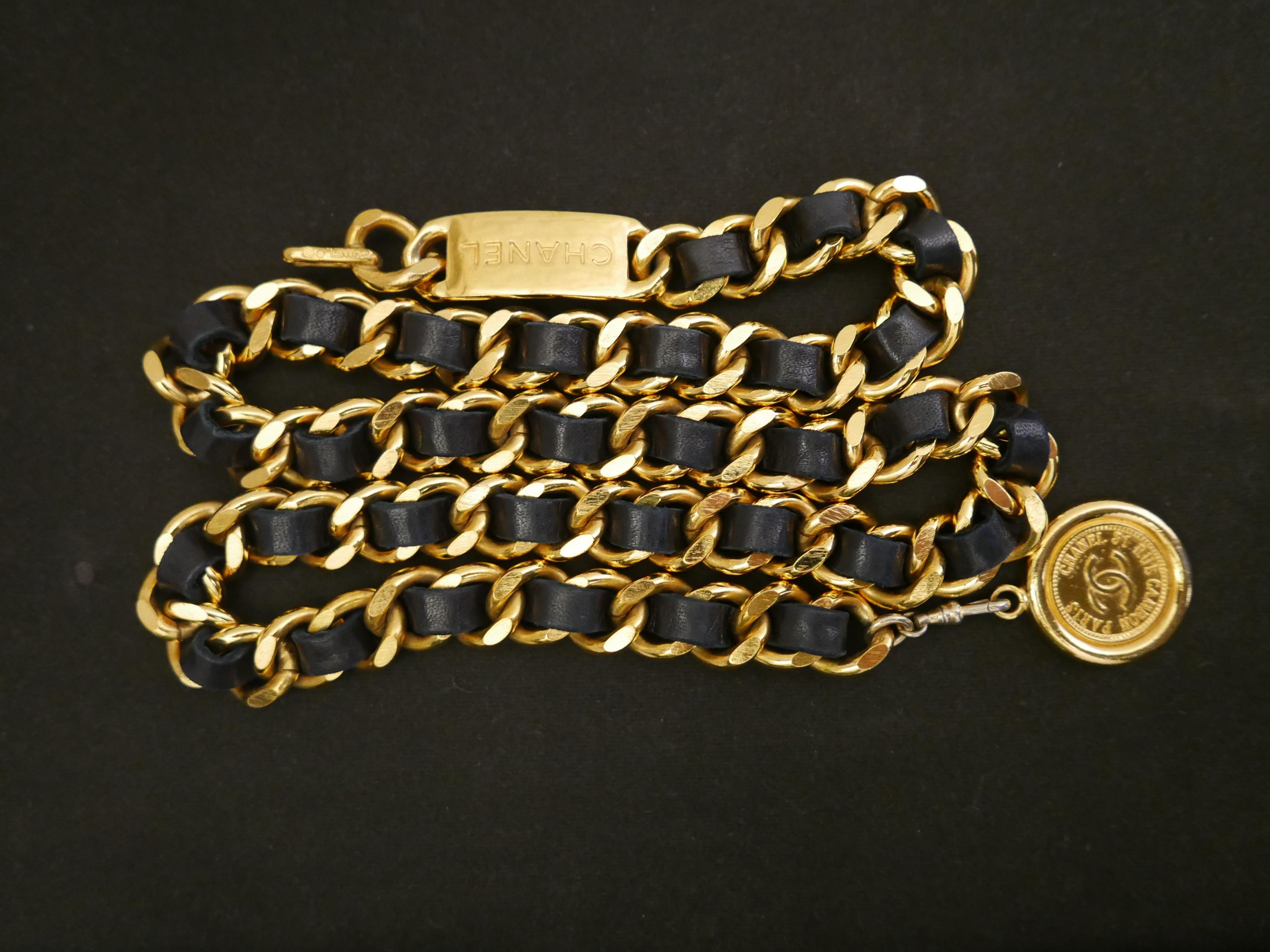 Vintage Chanel gold toned chain belt interlaced with black leather featuring a Coco coin charm. Stamped Chanel. Chain measures approximately 84 cm in length width 1.2 cm.

Condition - Minor signs of wear. Generally in good condition. Discoloration