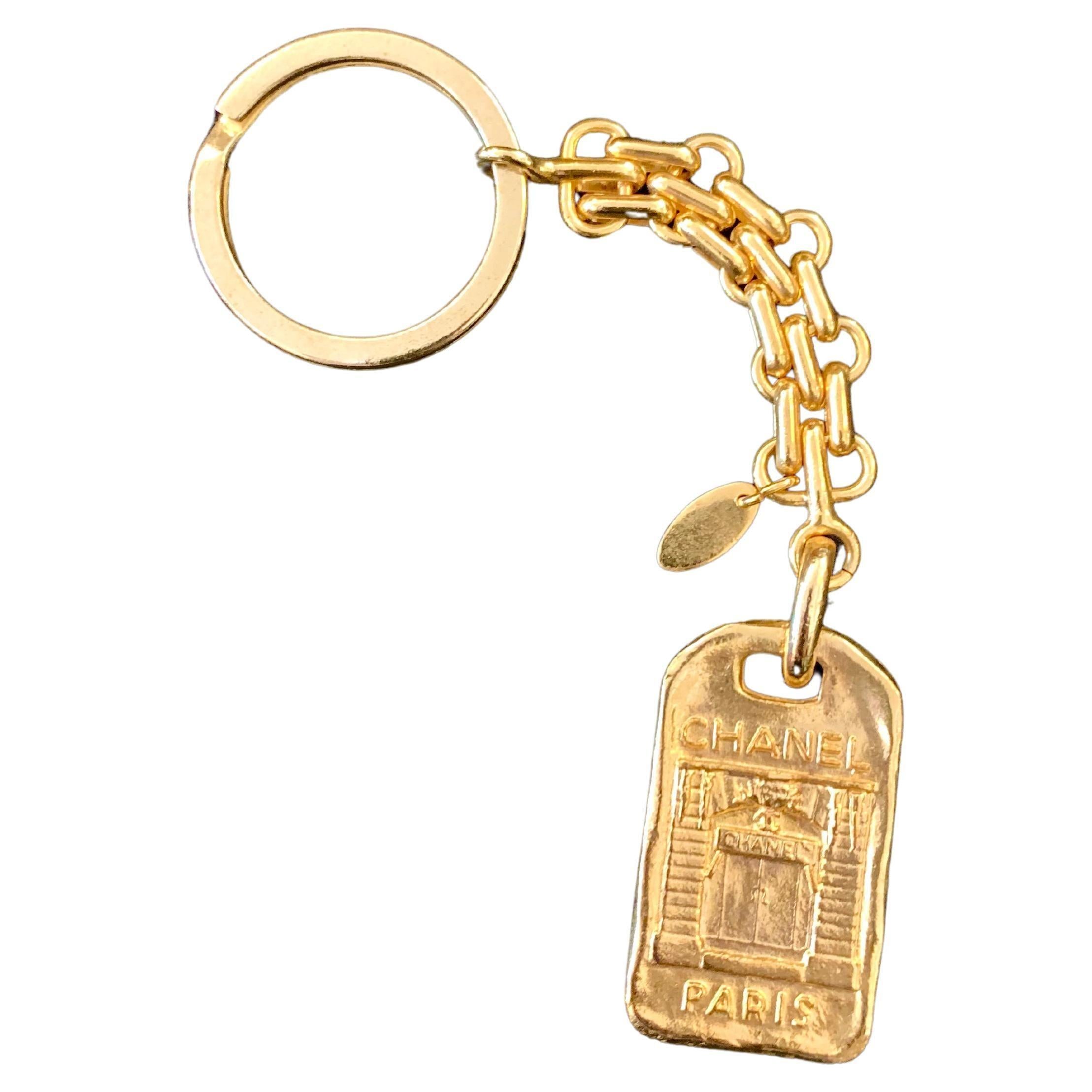 This vintage CHANEL key chain is crafted of gold toned metal featuring gold chain links with a key ring and a Chanel Paris front door charm plate. Stamped CHANEL Made in France. Length measures approximately 14 cm Charm 4.0 x 2.4 cm. Comes with