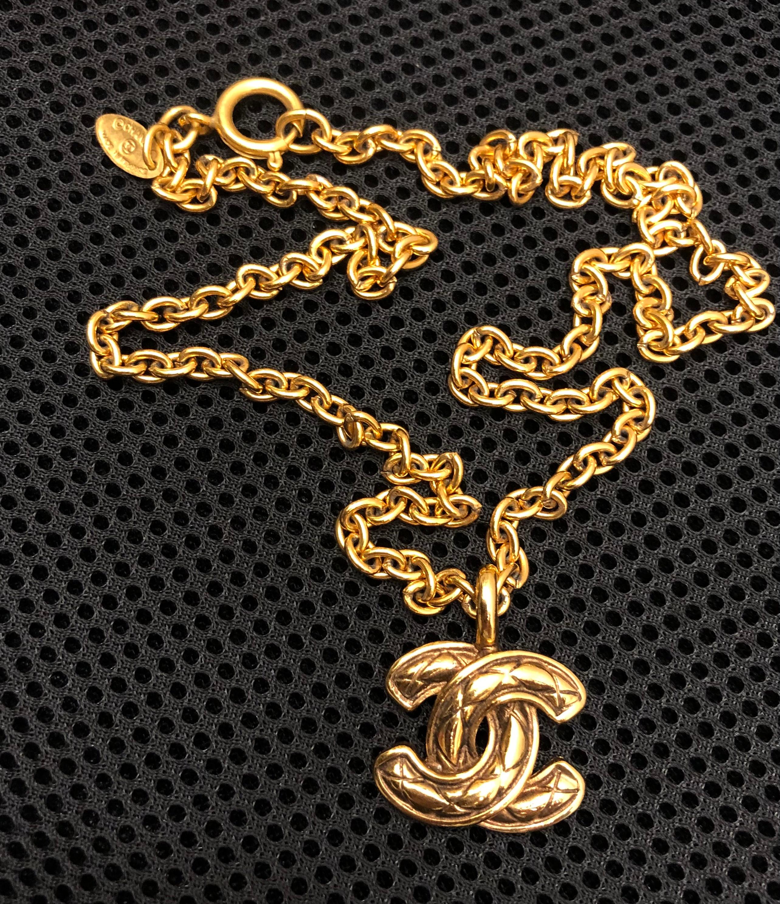 Ce collier Chanel vintage des années 1980 est réalisé en chaîne dorée et comporte une breloque CC matelassée dorée emblématique. Il s'agit du plus petit modèle de la série CC matelassée. Estampillé CHANEL fabriqué en France. Fermeture par anneau à