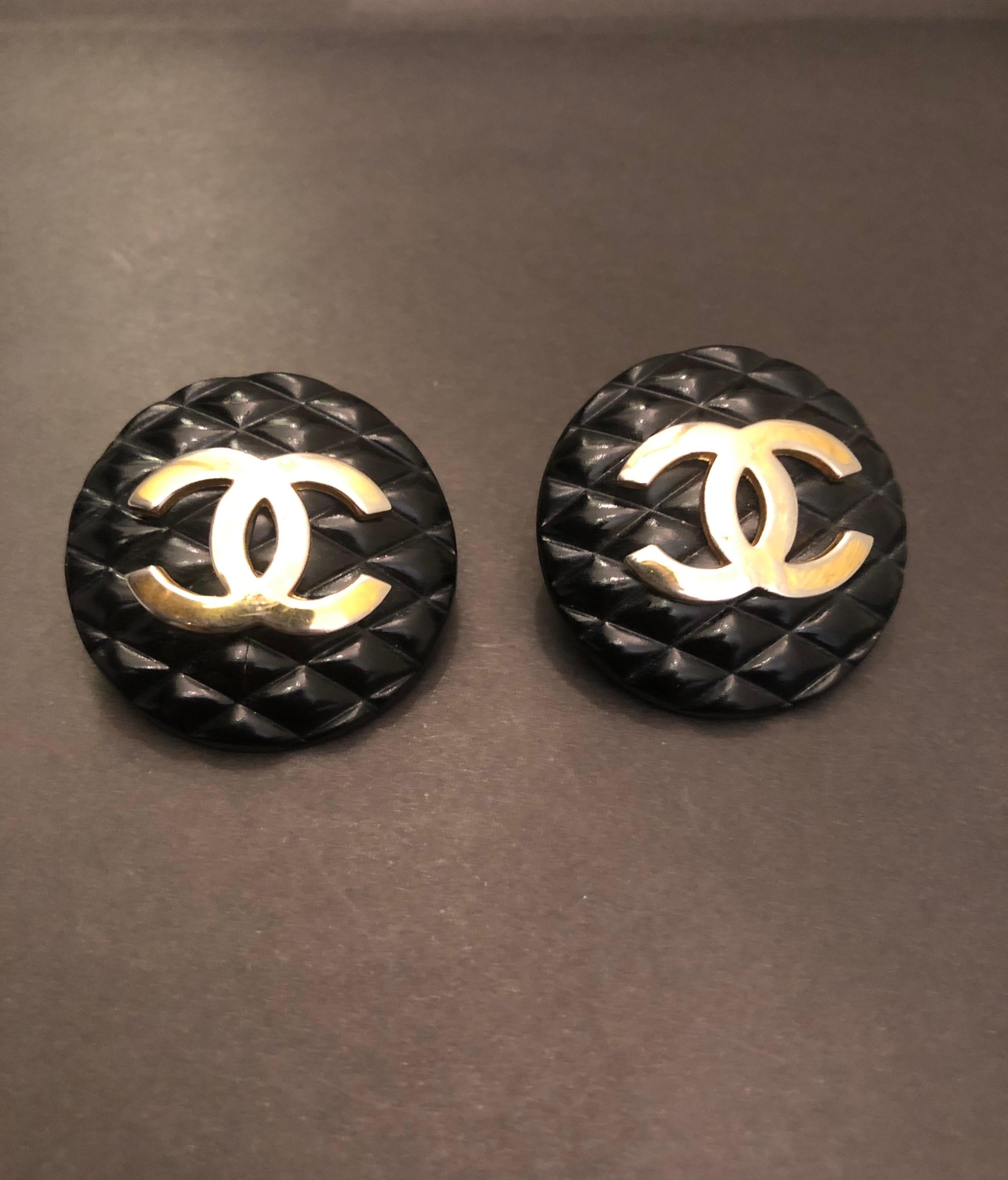 These 1980s vintage CHANEL massive button earrings are crafted of black resin in quilted pattern featuring a gold toned CC at the center. Stamped CHANEL 23 made in France. Measures approximately 3.4 cm in diameter. Come with box.

Condition - Good