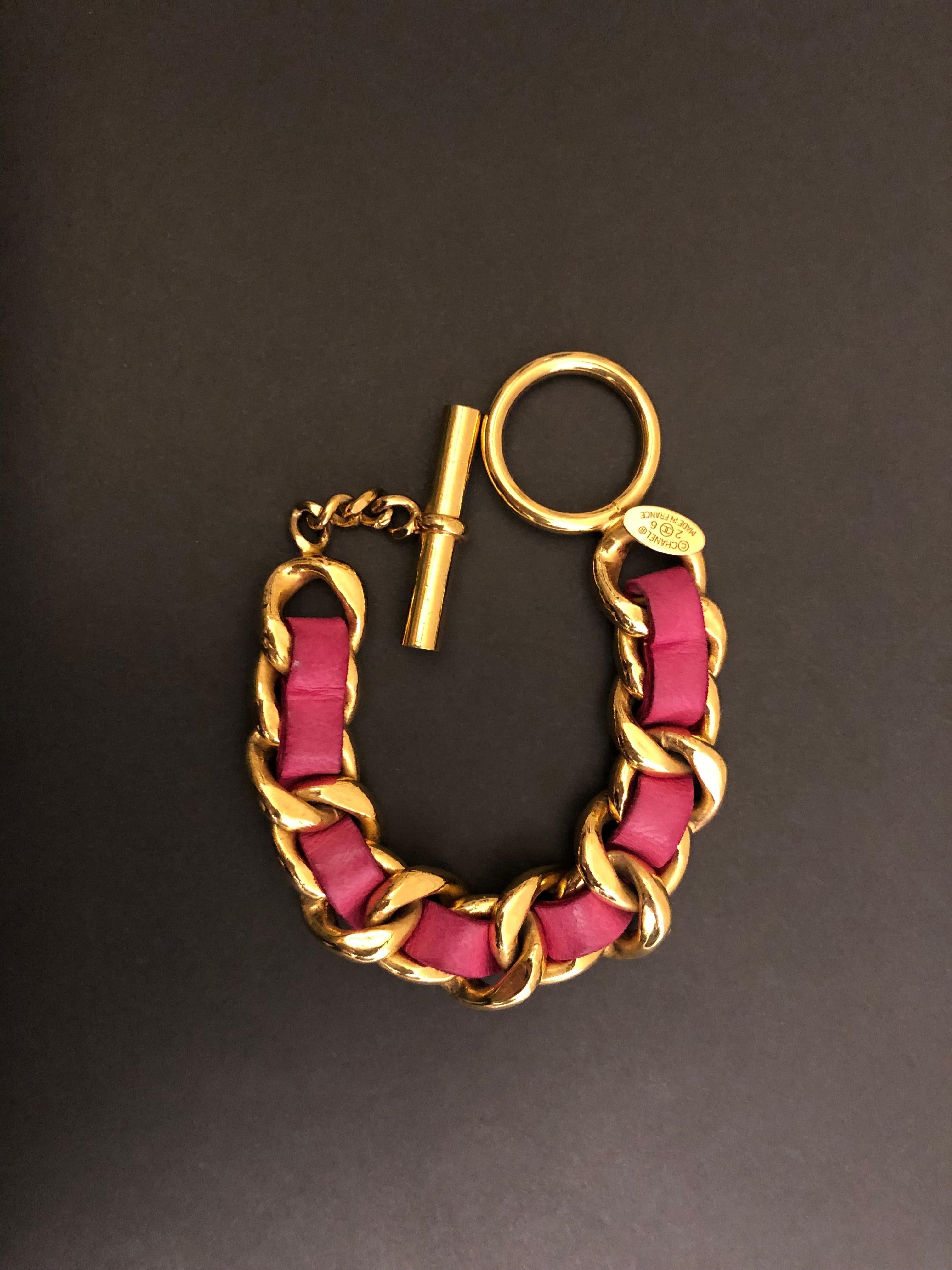 Vintage Chanel gold toned chain link bracelet interlaced with pink lambskin leather. Adjustable toggle fastening. Stamped CHANEL 26, made in France. Measures approximately 16 - 18 cm. Comes with box.

Condition: Some marks and discoloration on