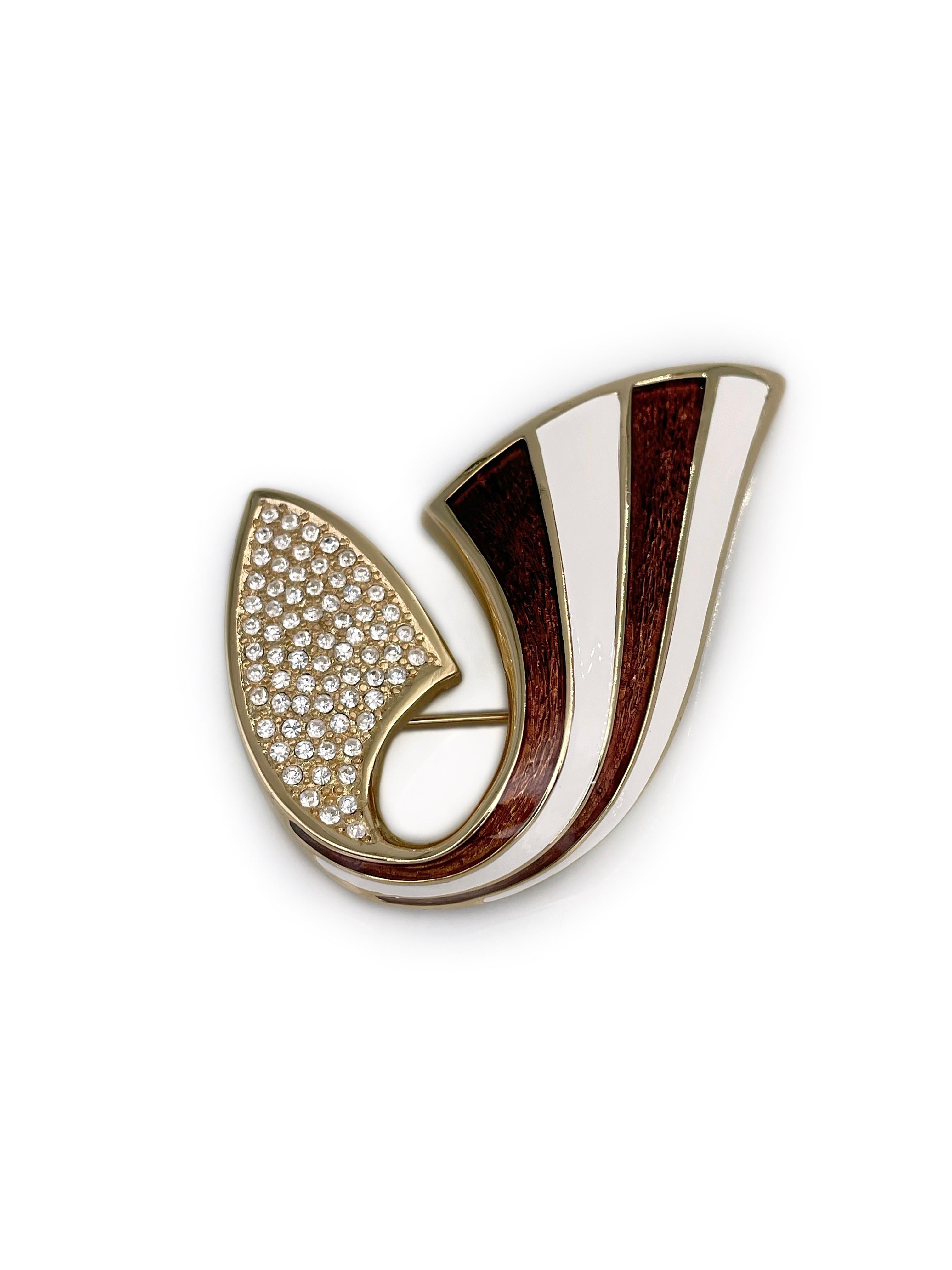 This is a vintage stylised ribbon brooch designed by Christian Dior in 1980’s. The piece is gold plated. It features clear rhinestones. The brooch is adorned with brown and white enamel.

Markings: “Chr. Dior©” (shown in photos).

Size: