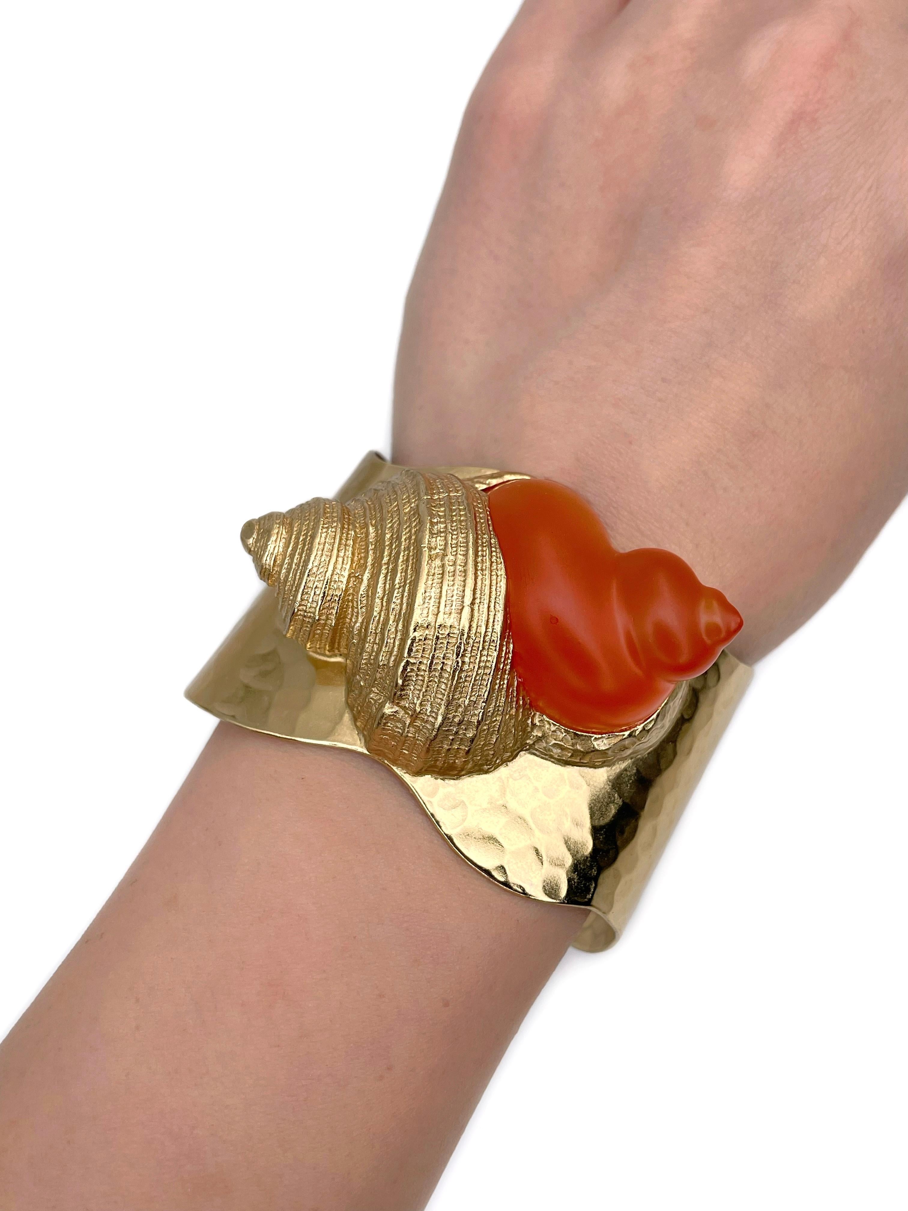 Dies ist eine gro�ße goldfarbene Muschel Motiv Manschette Armband. Es wurde von Robert Goossens für Christian Dior in den 1980er Jahren entworfen. Das Stück ist vergoldet, gepaart mit orangefarbenem Harz.

Markierungen: 