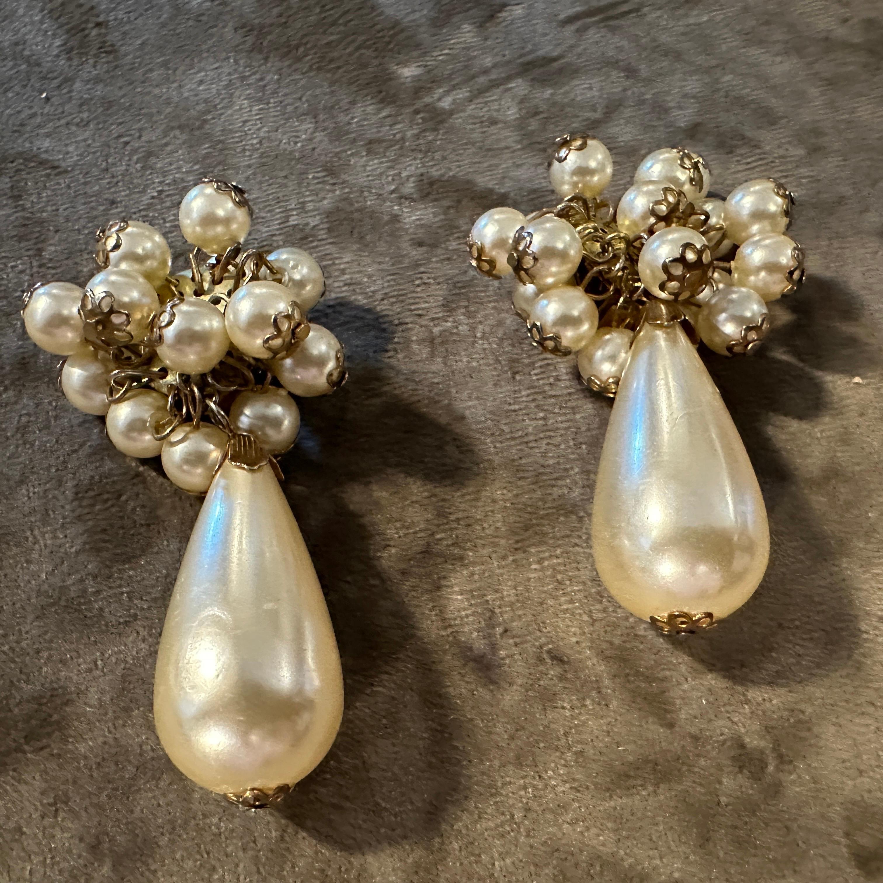 Chic 1980s Vintage Italienisch Faux Perle Cluster baumeln Clip-On Ohrringe
Diese wunderschönen, aus Italien stammenden Vintage-Ohrclips aus den 1980er Jahren sind raffiniert. Sie zeichnen sich durch eine reizvolle Ansammlung von schimmernden