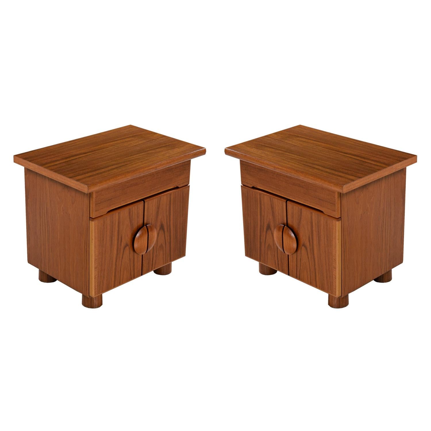 This is a very special pair of Danish teak nightstands. Produced in the latter part of the 20th century, the stout bedside tables move away from the dainty Danish modern look. The designer broadened the legs and added a graceful circular handle.