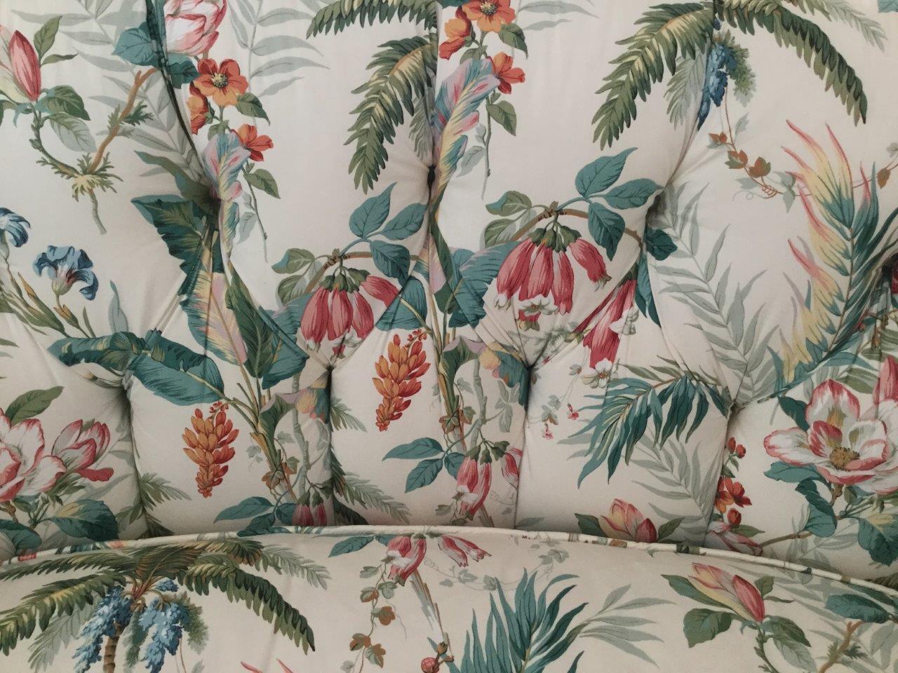 Romantic and comfy English chintz love-seat. With a high, rounded back, this piece is custom upholstered in an English cotton print. In this print you will find palm leaves and other foliage in many shades of green, blue, and aqua. The raspberry
