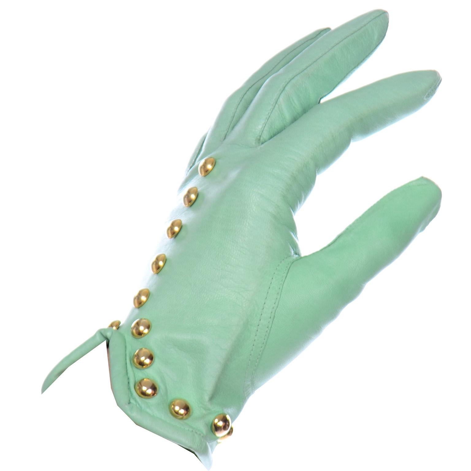 These vintage Escada mint green leather gloves have beautiful round gold tone studs along the wrist and the top of the hand. These super soft leather gloves are V shaped  on the top of the wrist and are stamped size 7 1/2 on the interior. Made in