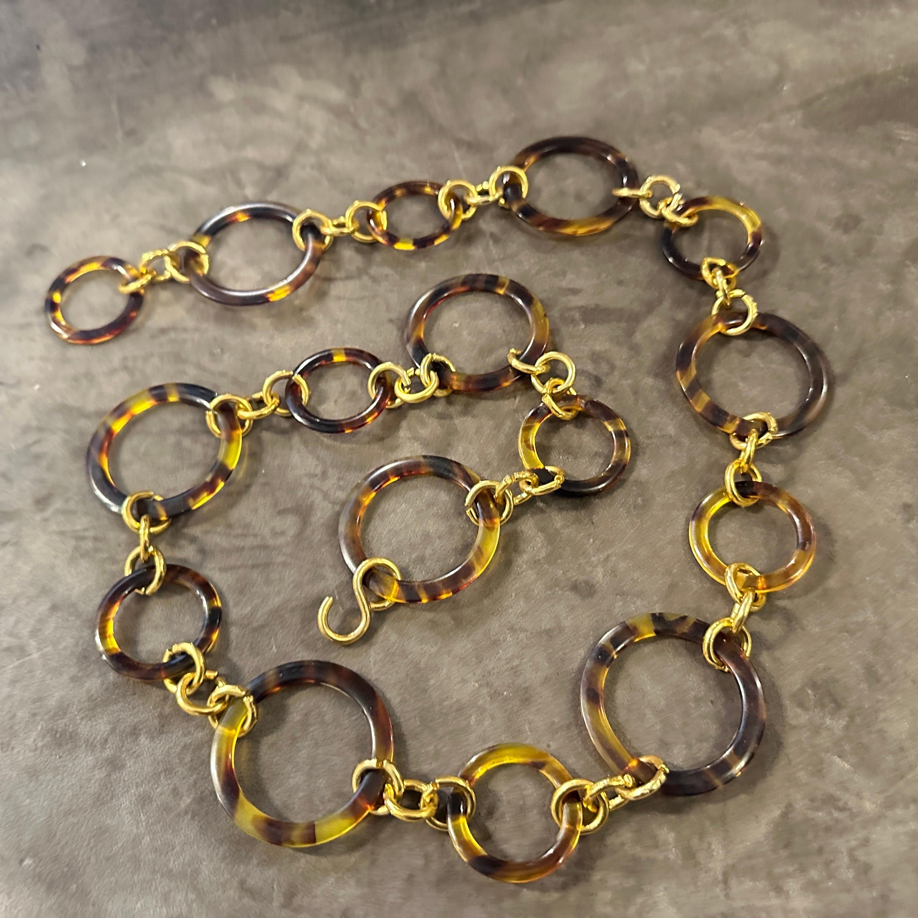 This is a statement fashion belt from the 1980s, showcasing a bold and glamorous aesthetic. It features a series of interconnected links made from two distinct materials faux tortoiseshell lucite and a gold-toned brass, showcasing a bold and