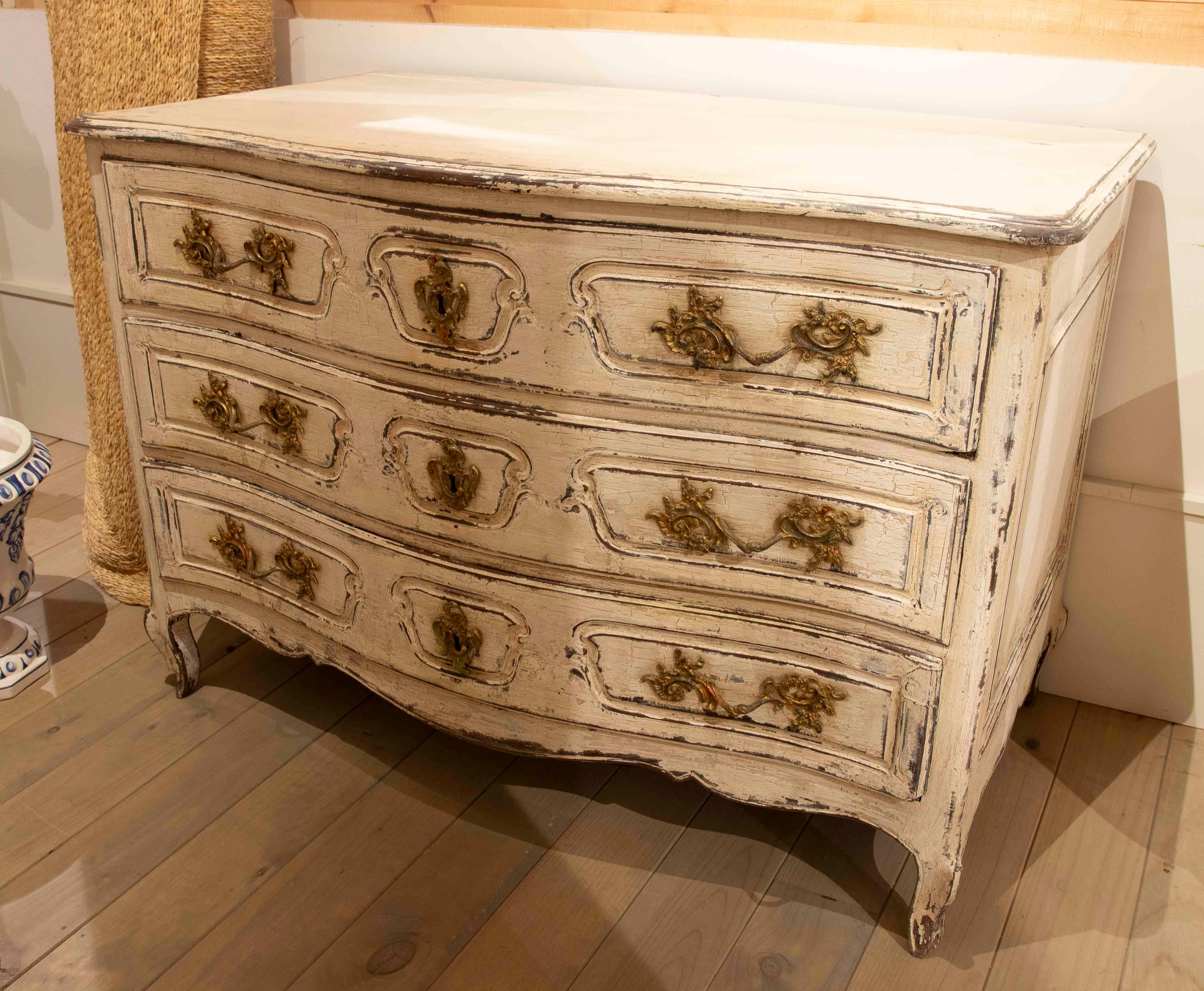 Elegante Kommode im französischen Stil mit charmantem Antik-Finish, das ihren Vintage- und handwerklichen Charakter unterstreicht. Es hat drei breite Schubladen, die mit geschwungenen Leisten und Ziergriffen klassischer Inspiration in Goldtönen