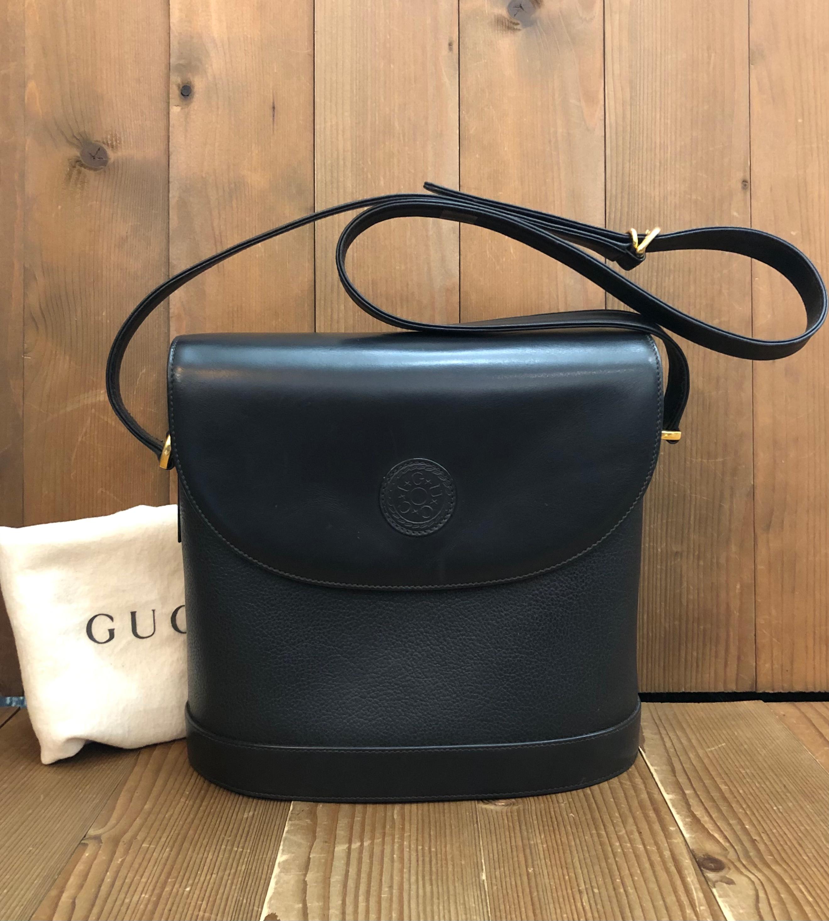 Ce sac à bandoulière box bucket vintage de Gucci est réalisé en cuir de veau lisse et grainé de couleur noire et doté de ferrures dorées. La fermeture magnétique frontale s'ouvre sur un luxueux intérieur en daim doté d'une pochette zippée.