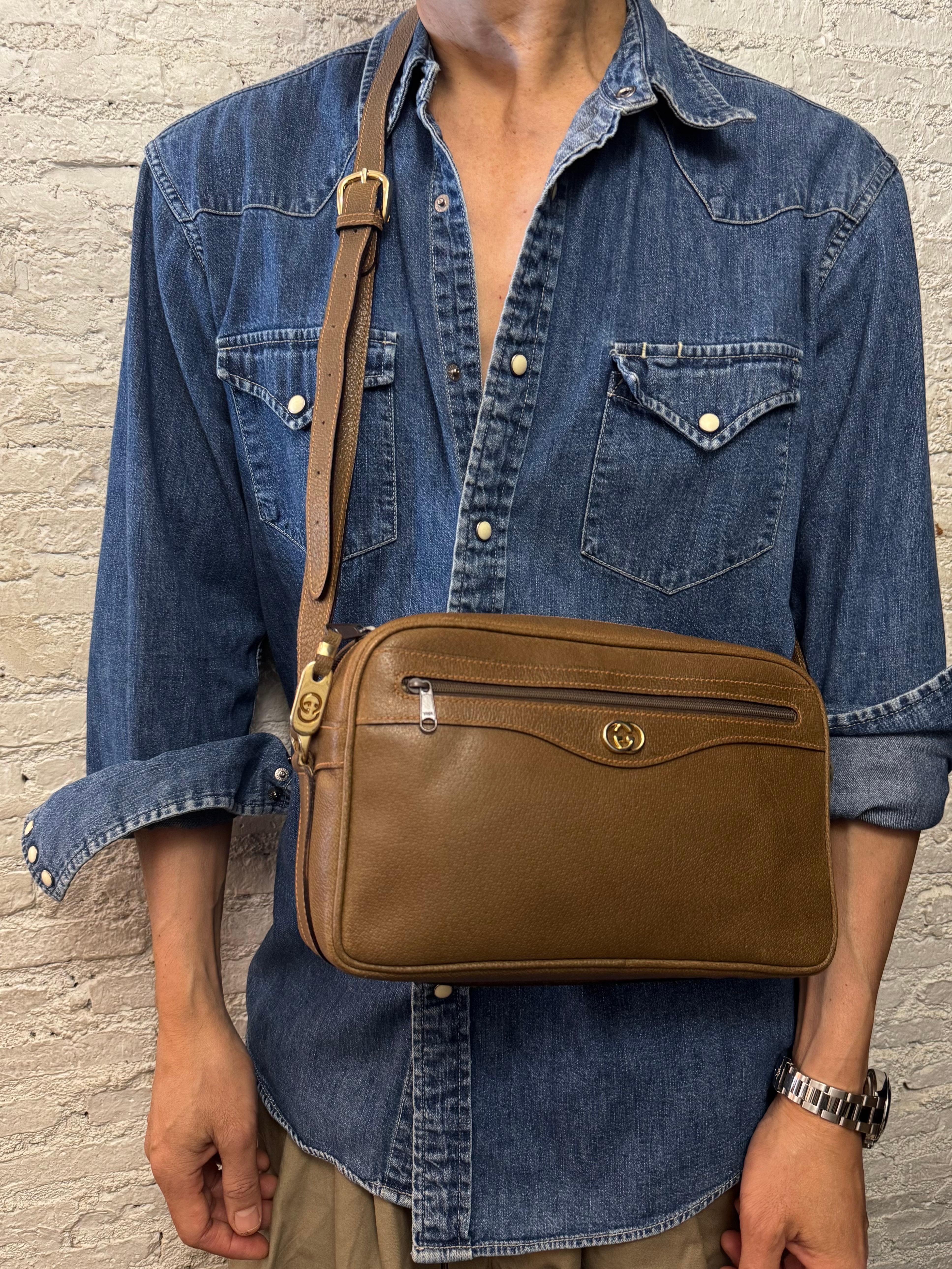 Esta bolsa vintage para cámara GUCCI está fabricada en piel de cerdo marrón y herrajes dorados. El cierre de cremallera superior se abre a un interior de piel beige con un bolsillo con cremallera. Este Gucci también tiene un bolsillo con cremallera