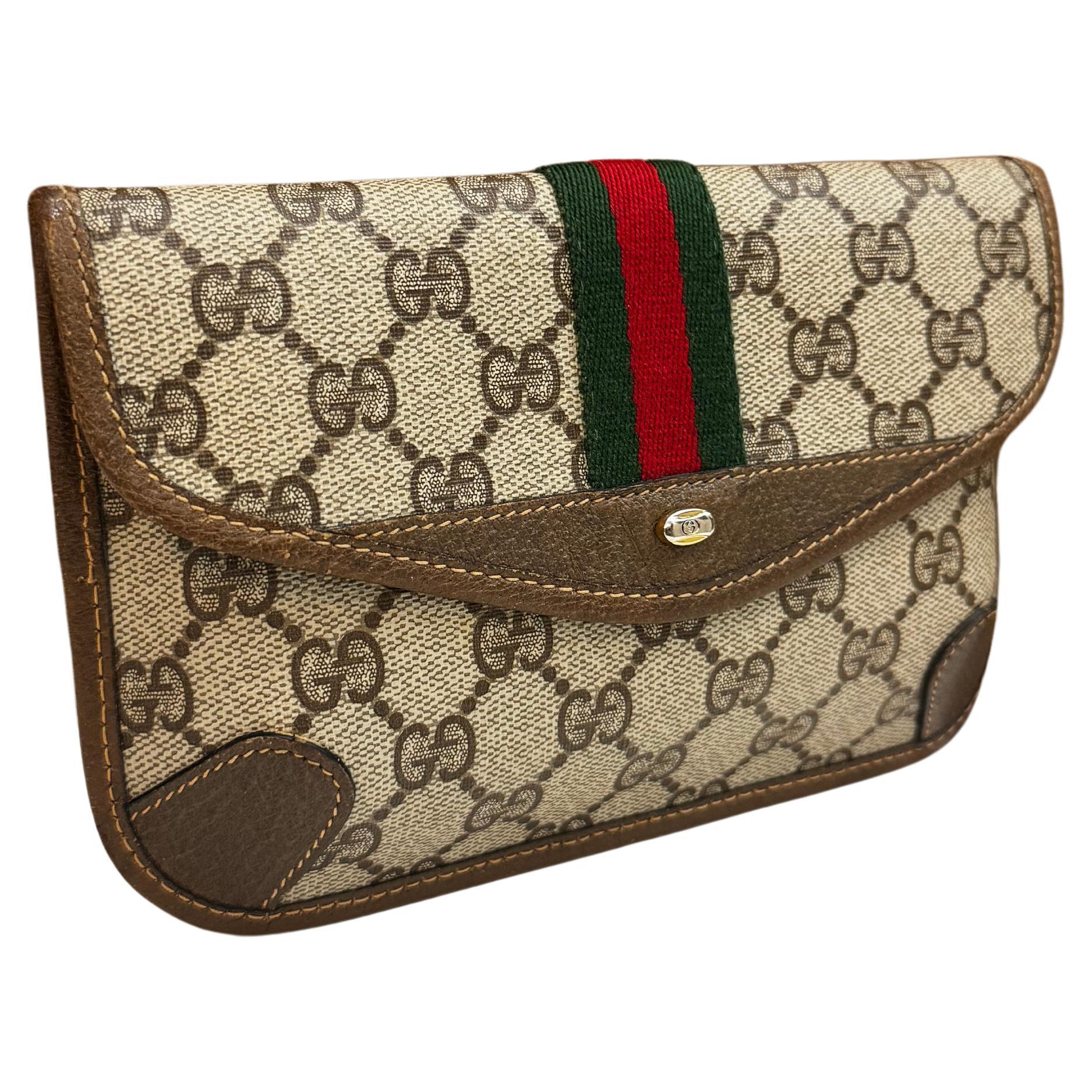 This vintage GUCCI pouch bag is crafted of GG monogram canvas in brown trimmed with brown pigskin’s leather. Front snap closure opens to an un-lined interior. Made in Italy. Measures approximately 7.5 x 5 x 0.5 inches.

Condition - Excellent vintage