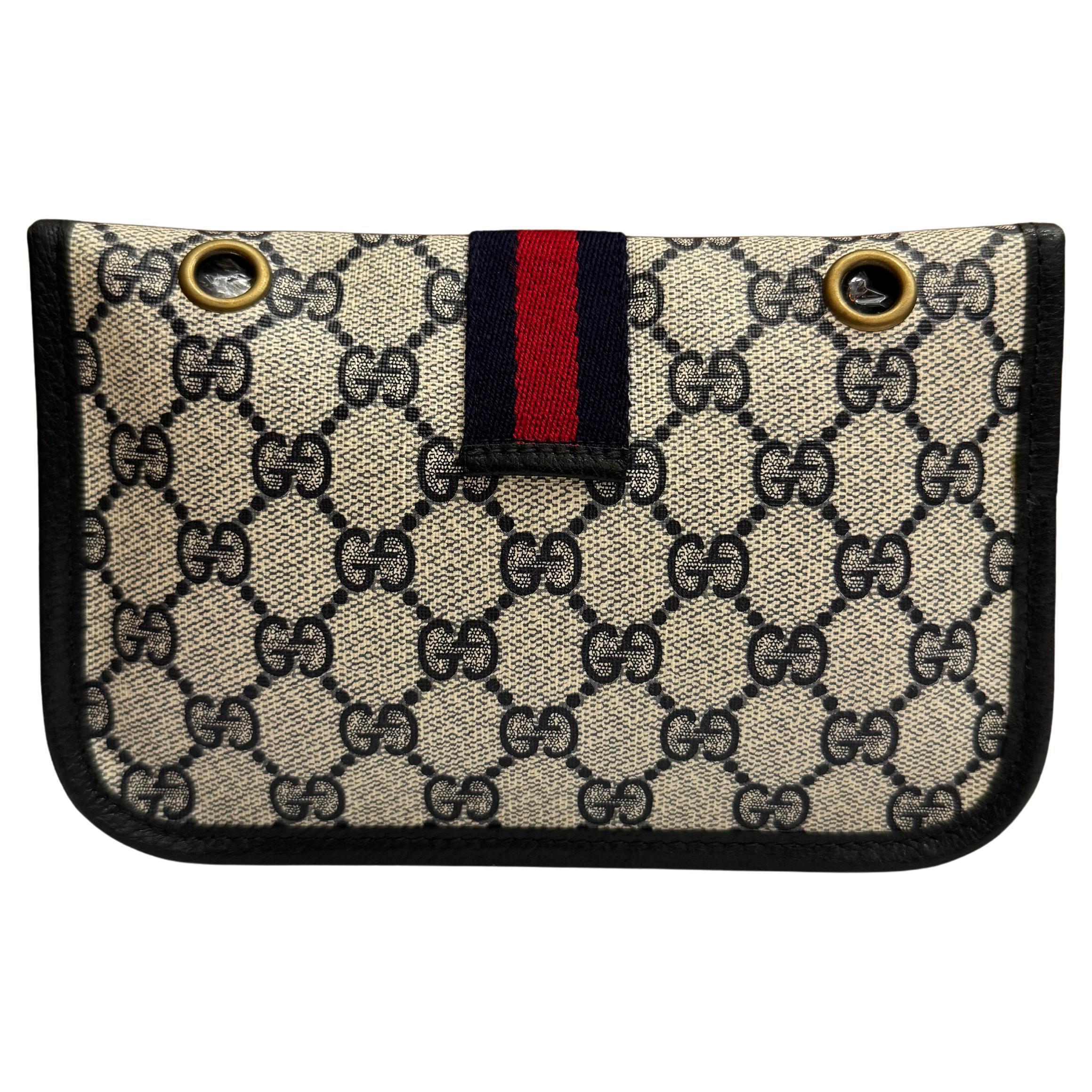 This vintage GUCCI pouch bag is crafted of GG monogram canvas in navy trimmed with navy pigskin leather. Front snap closure opens to an un-lined interior. This pouch has been altered by adding metal eyelets on the back to secure a crossbody chain.
