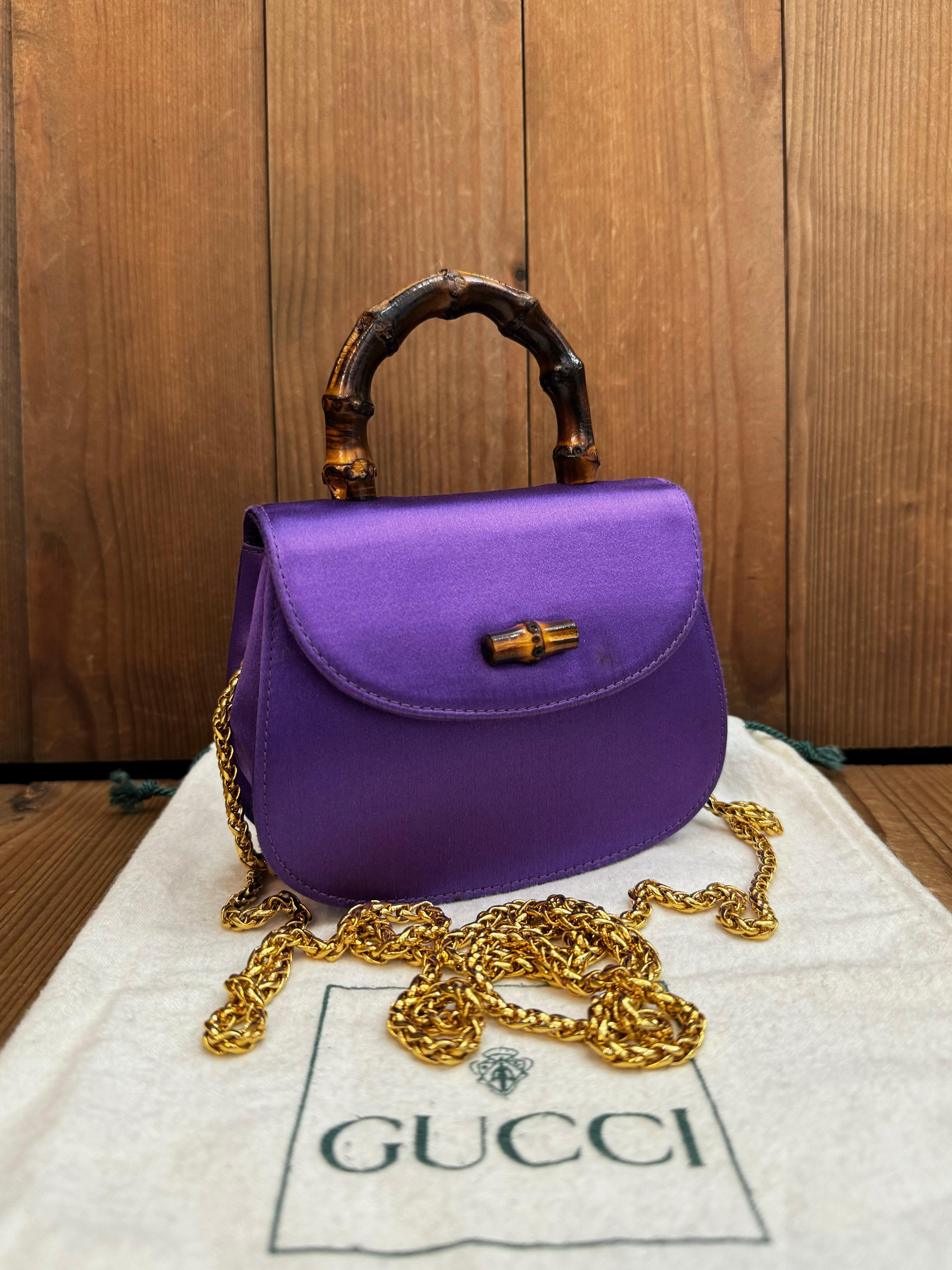 This vintage GUCCI micro two-way evening handbag is crafted of silk satin in purple and a bamboo handle featuring gold toned hardware. Front flap magnetic bamboo snap closure opens to a satin interior with a patch pocket. This micro bamboo bag also