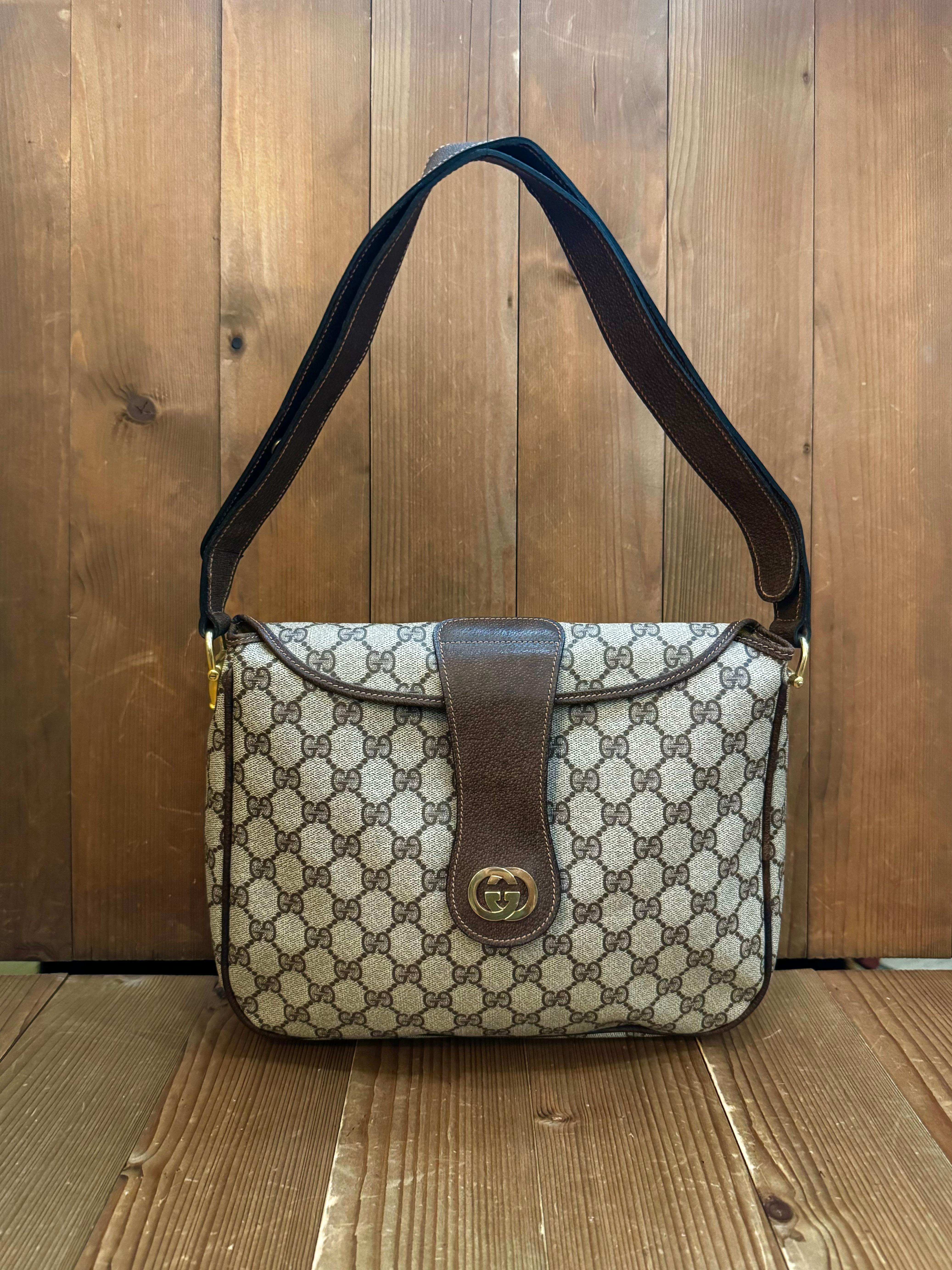 This vintage GUCCI shoulder bag is crafted of GG monogram coated canvas and pigskin leather in brown featuring gold toned hardware. Front snap closure opens to a diamante jacquard interior with a zippered pocket. This shoulder bag features an