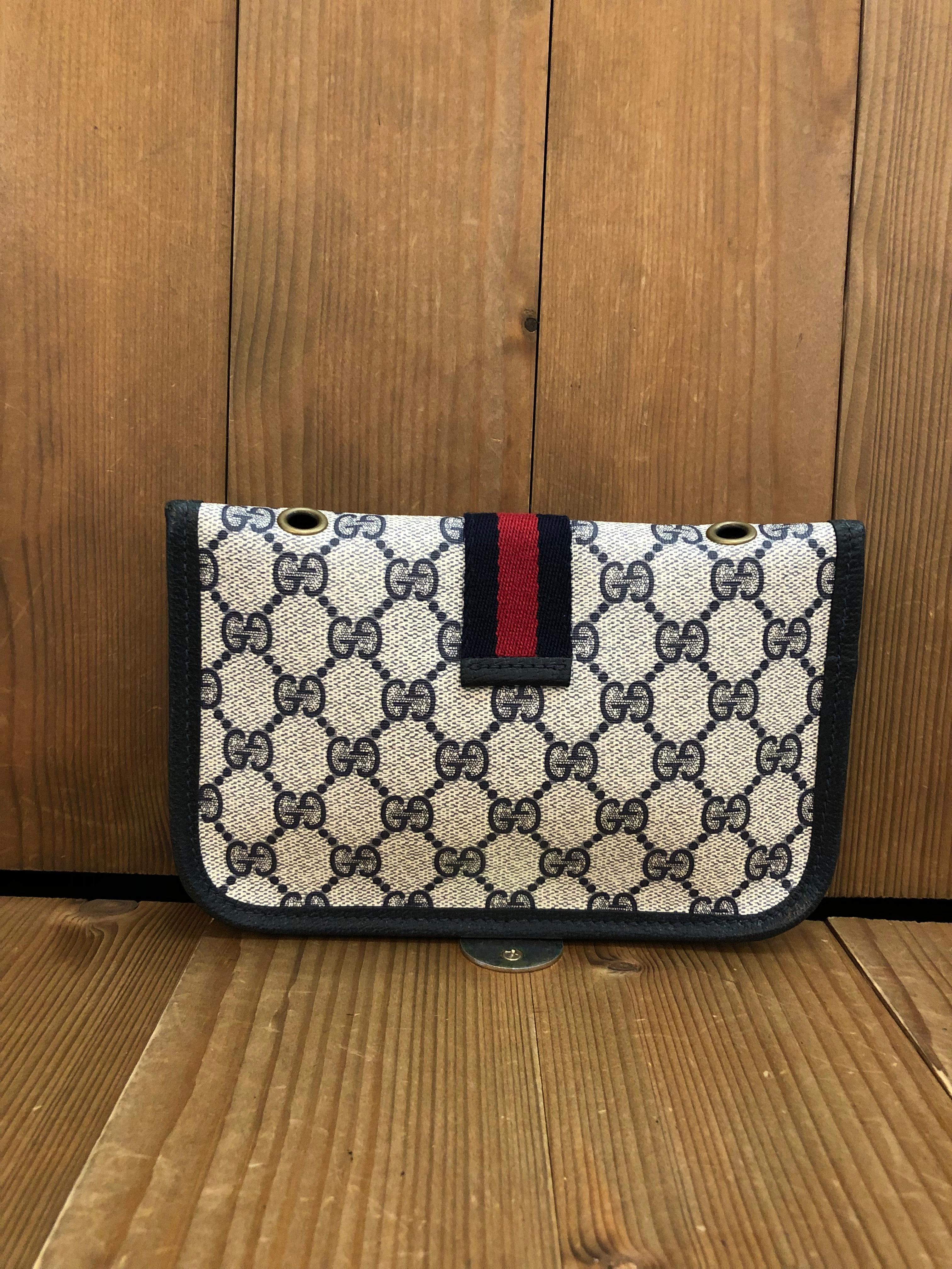 This vintage GUCCI pouch bag is crafted of GG monogram canvas in navy trimmed with navy leather. Front snap closure open to an un-lined canvas interior. Made in Italy. Measures 7.5 x 5 x 0.5 inches. This pouch has been altered by adding third party