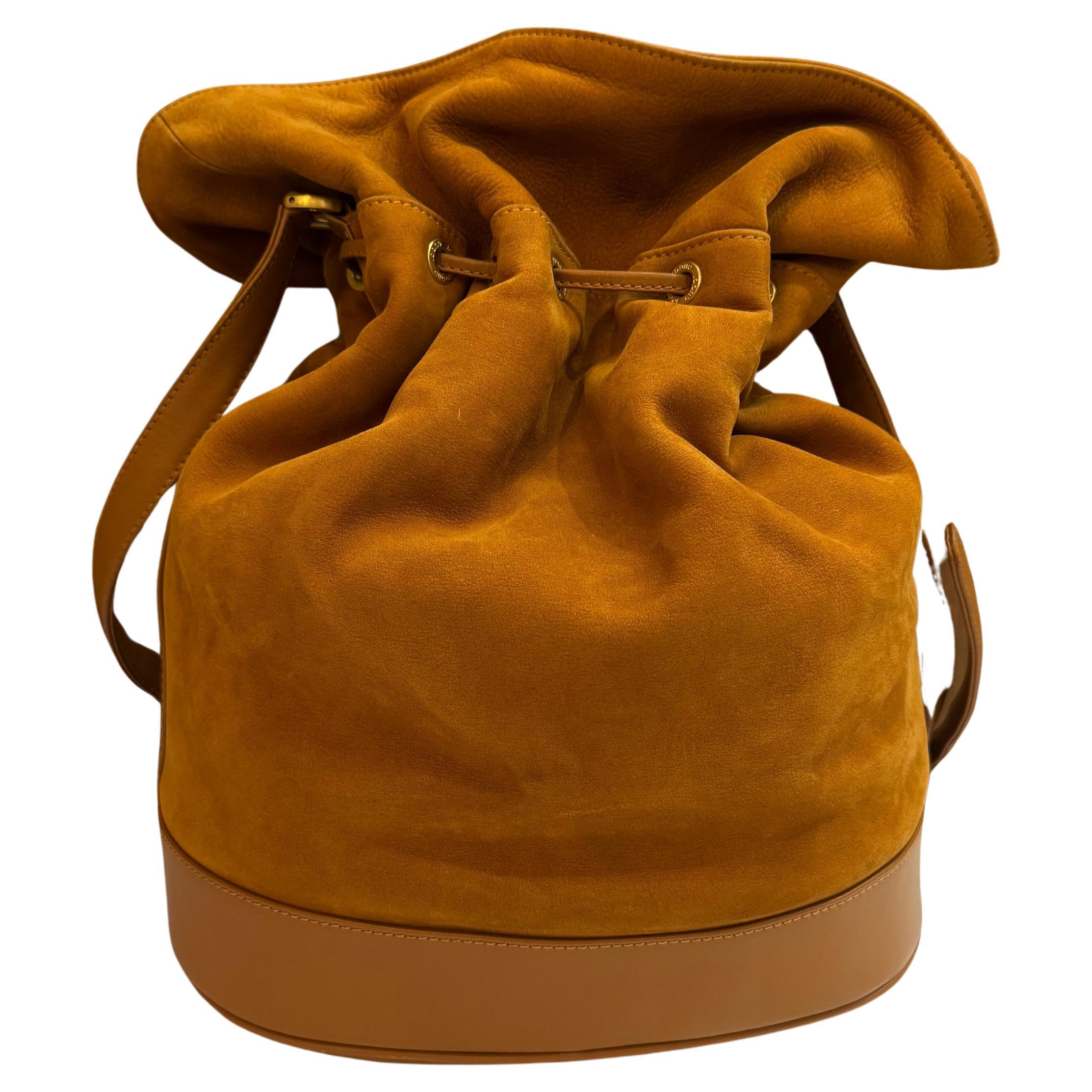 This vintage GUCCI bucket bag is crafted of grained nubuck calfskin leather in caramel brown and smooth calfskin leather featuring gold toned hardware. Top drawstring closure opens to a spacious diamante jacquard interior in brown featuring a
