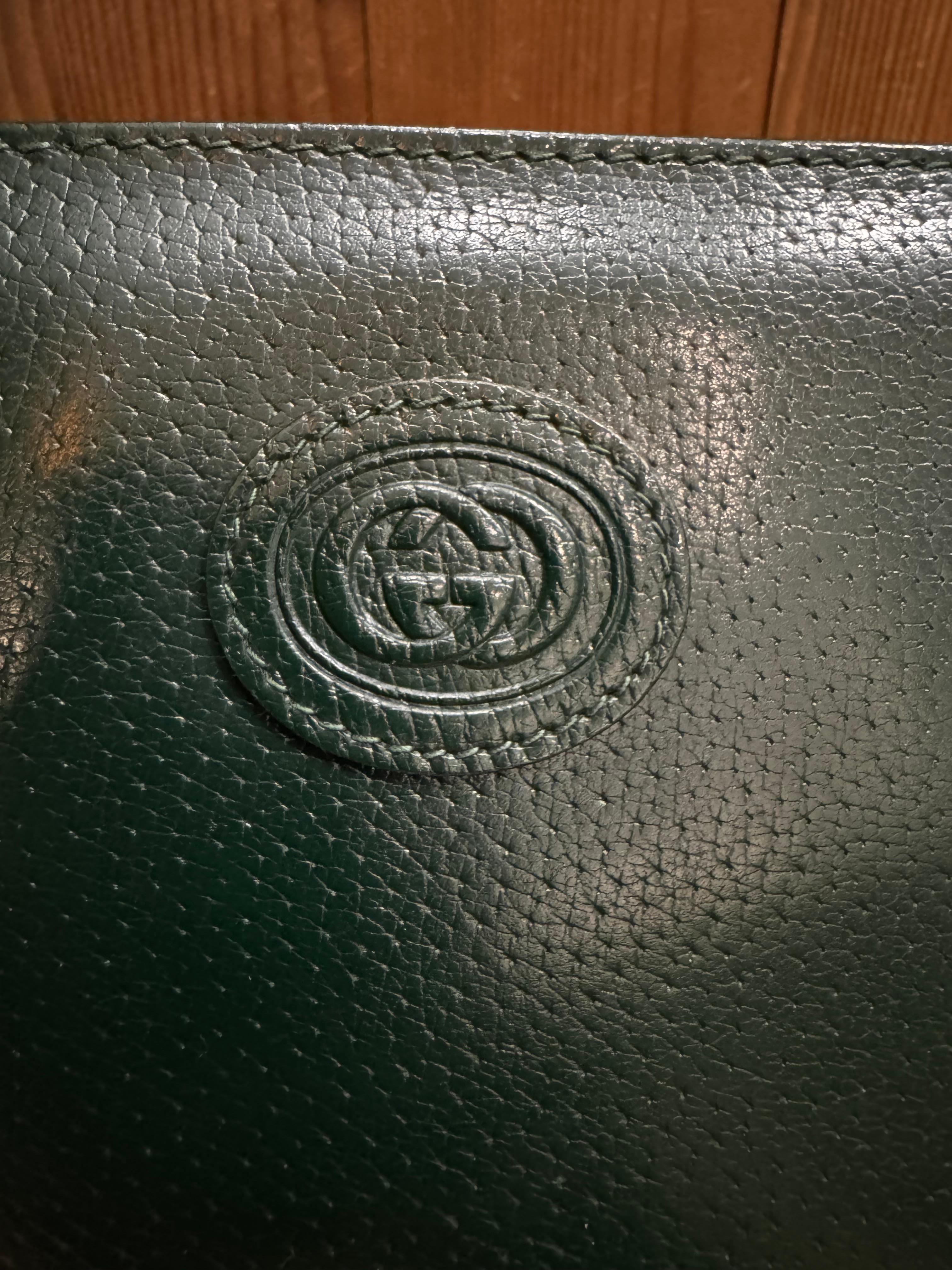 This vintage GUCCI mini book tote is crafted of pigskin leather in hunter green and enameled hardware. Top zipper closure opens to a dark green nubuck leather interior featuring a zippered pocket. Made in Italy. Measures approximately 8.5 x 10 x 2.5